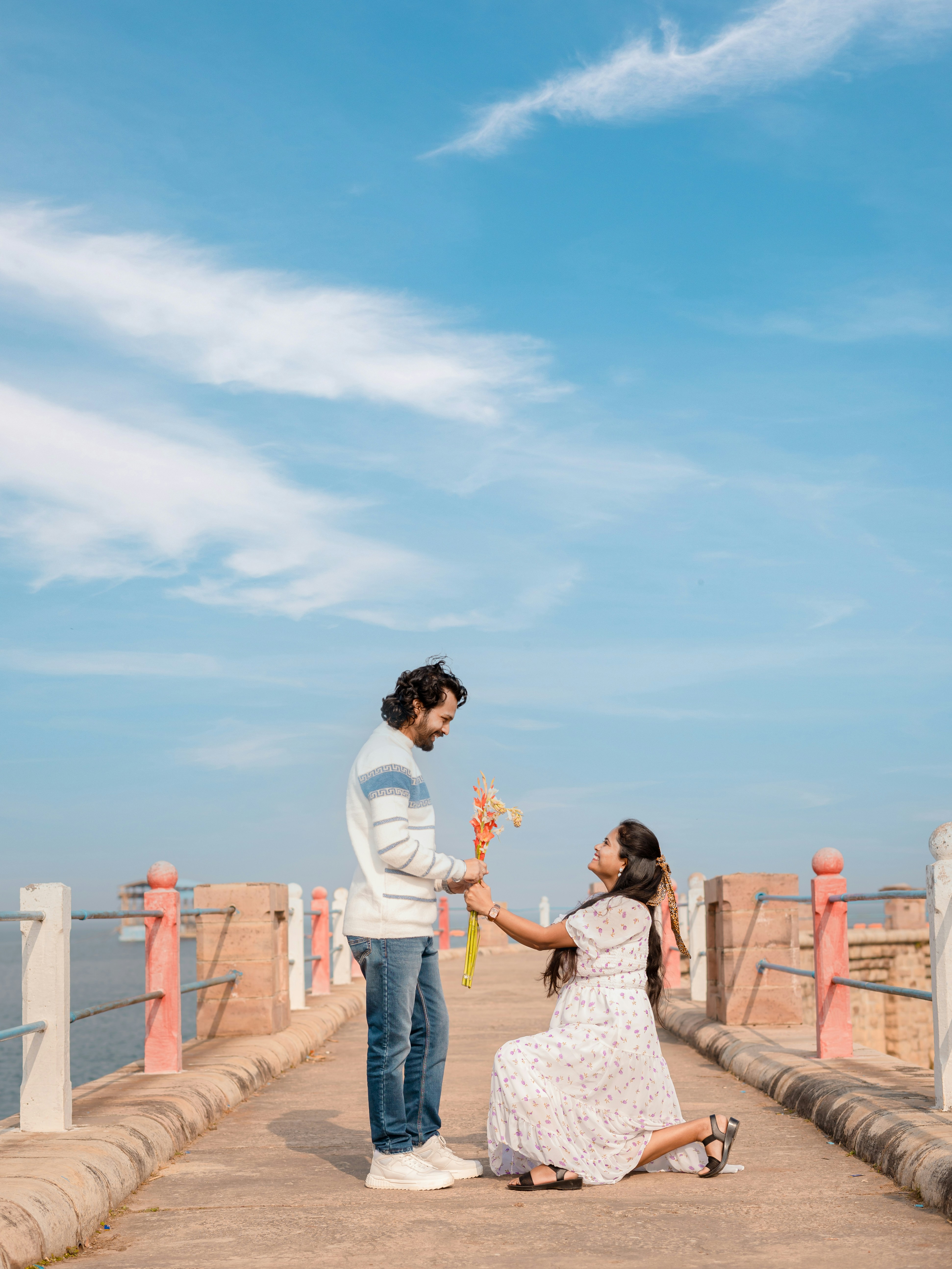 Ein Paar auf einem Pier, bei dem eine Person einen Antrag macht