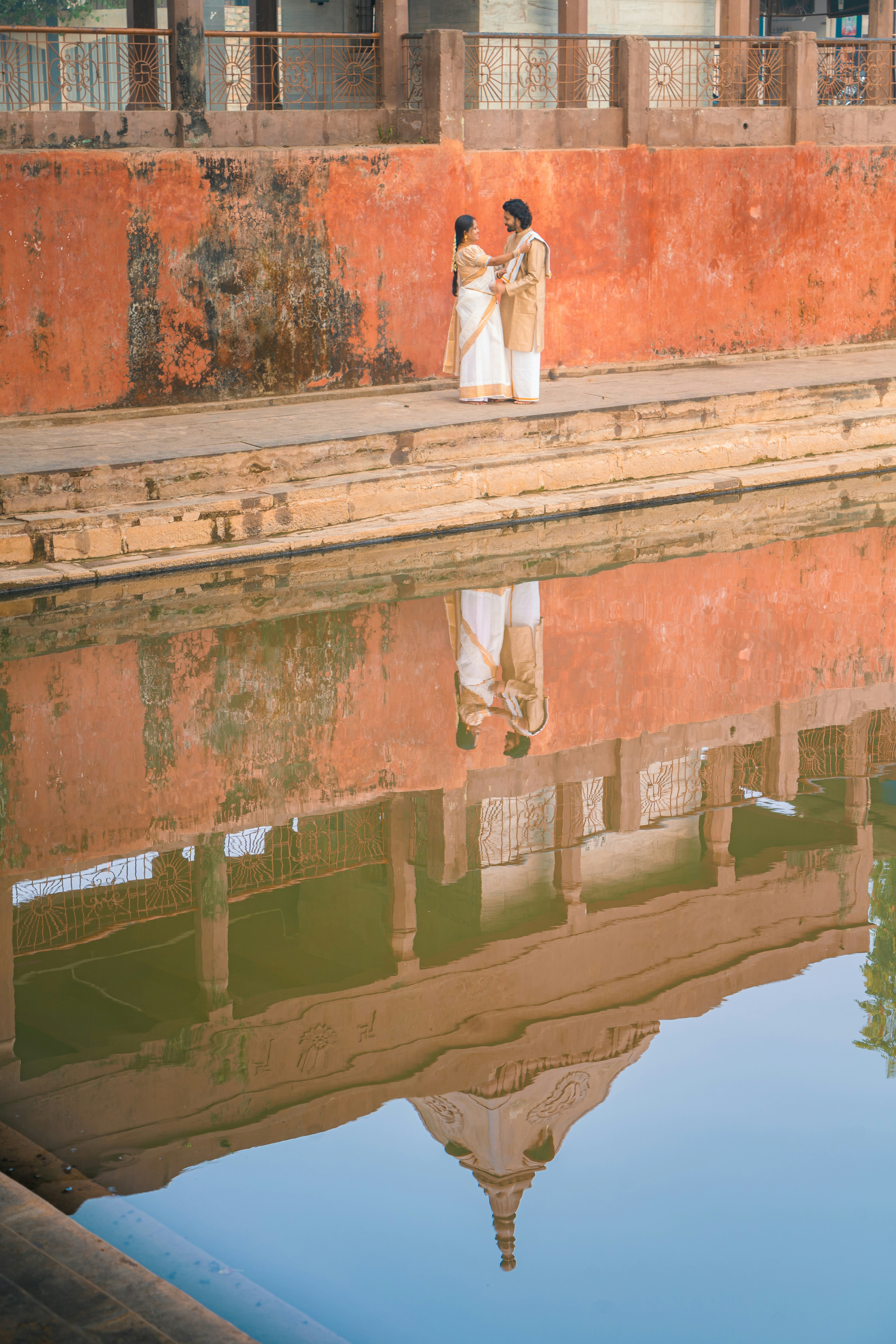 Paar in traditioneller indischer Kleidung, spiegelt sich im Wasser.