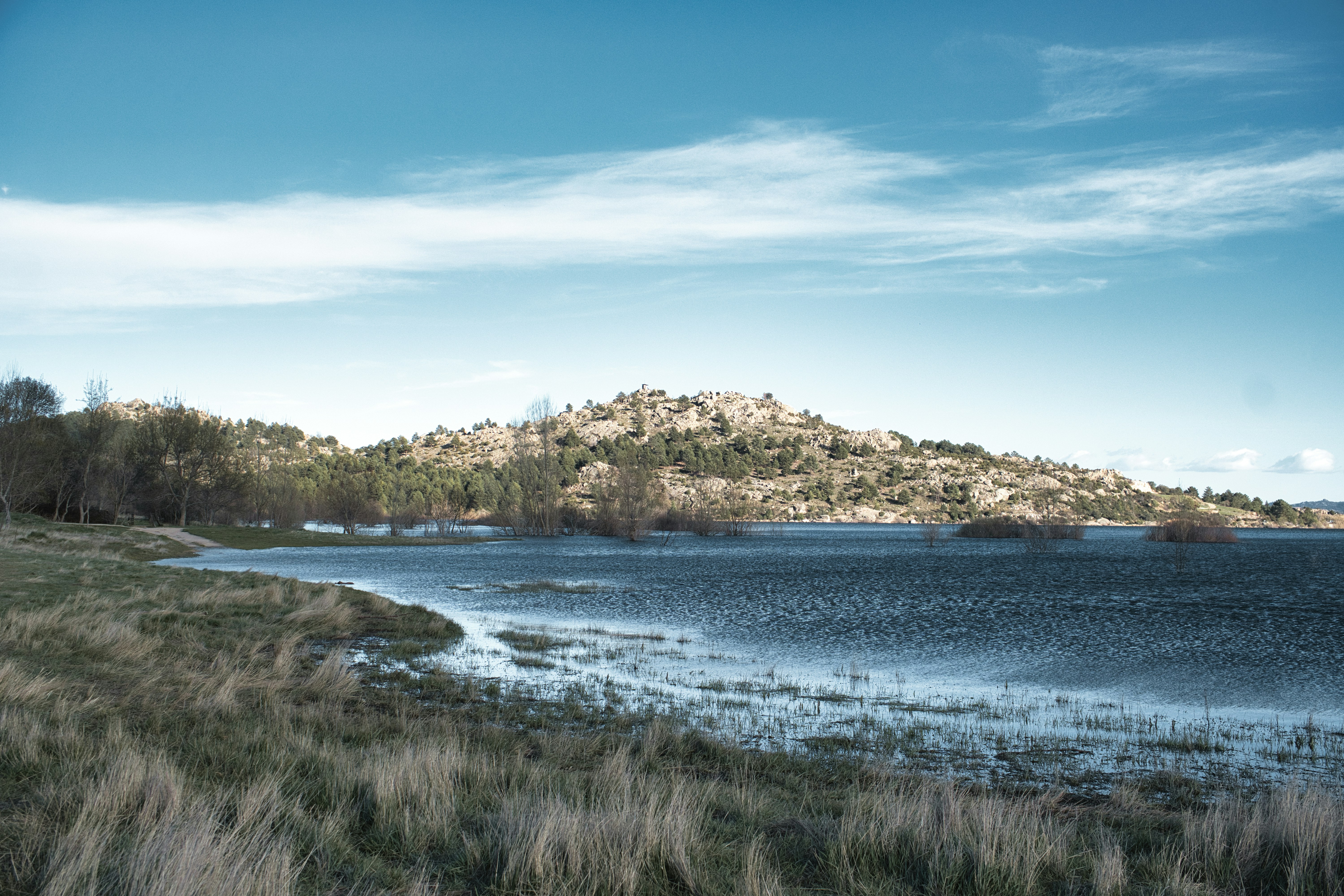 A calm lake with a rocky hill in the background.