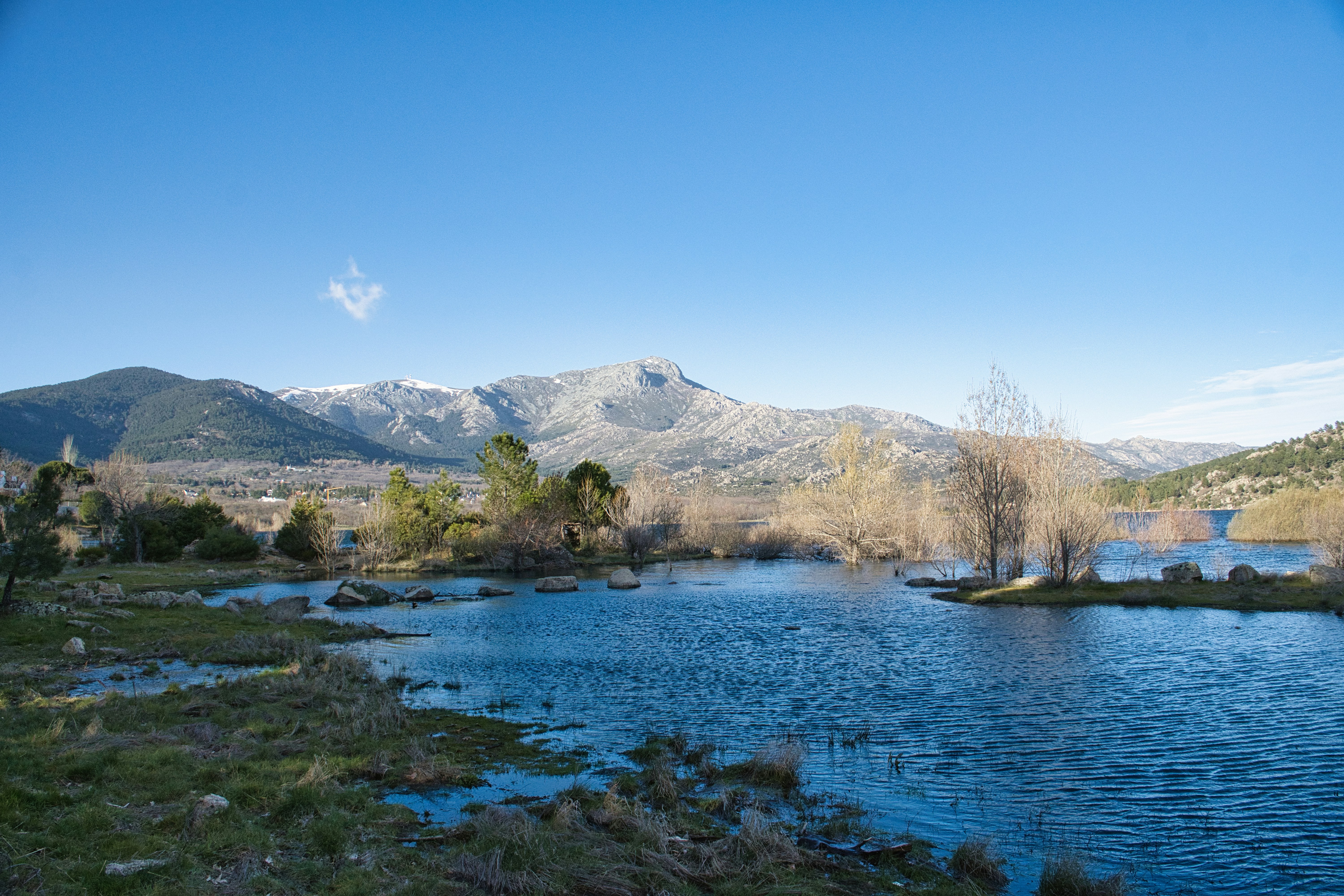 Snow-capped mountains overlook a serene lake under a clear sky.