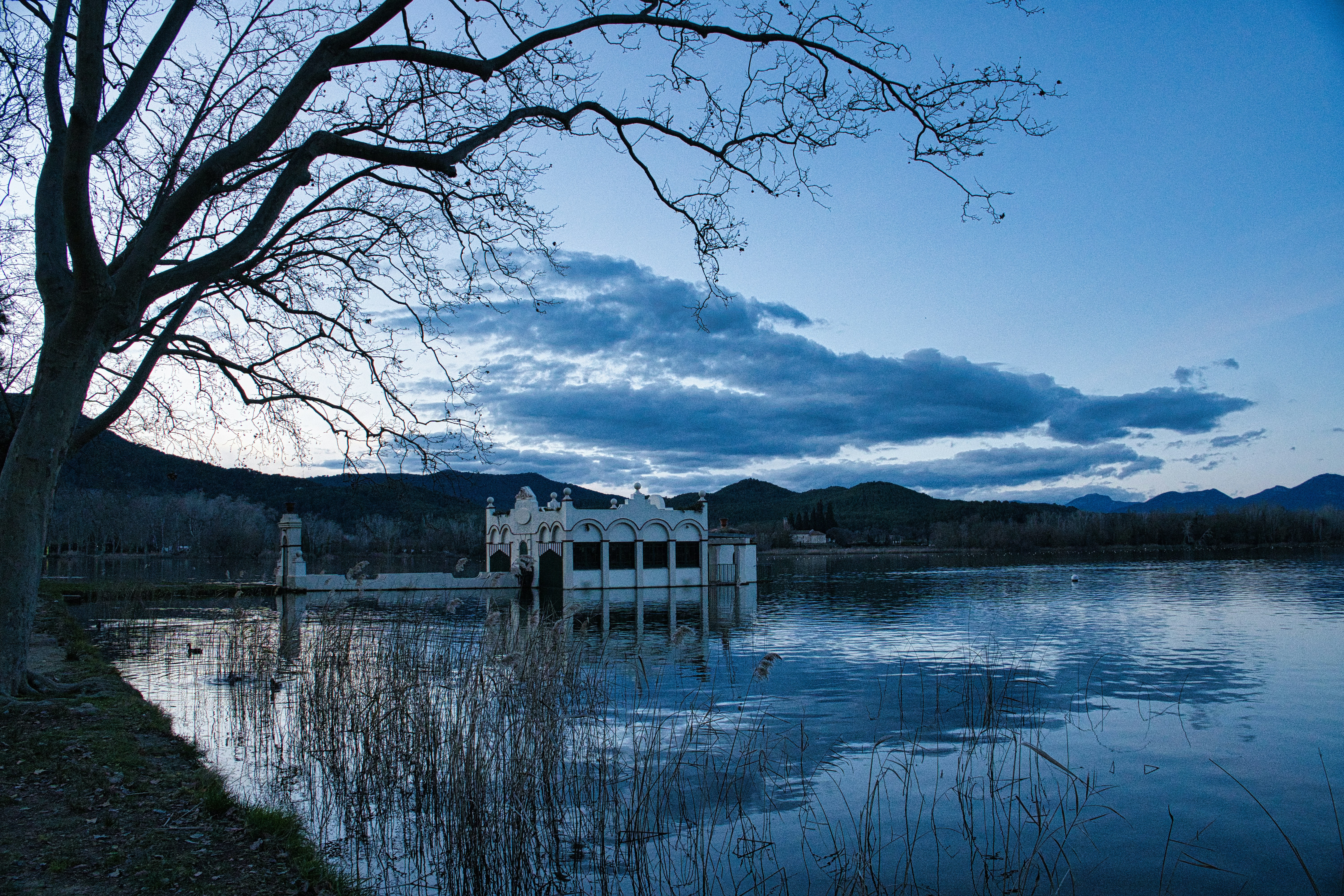 White building reflected in calm water at dusk.