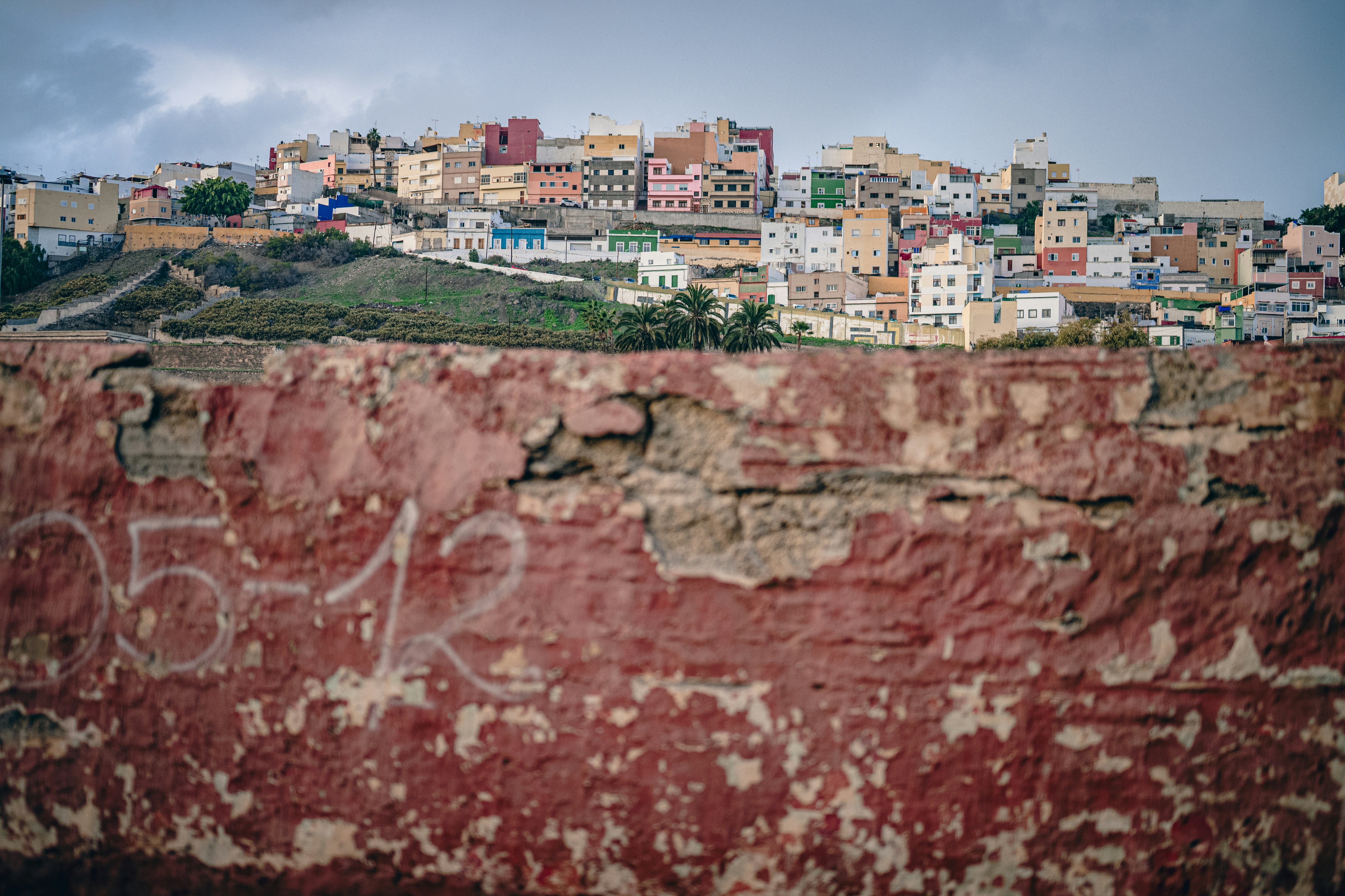 Colorful buildings on a hillside overlooking a distressed wall.