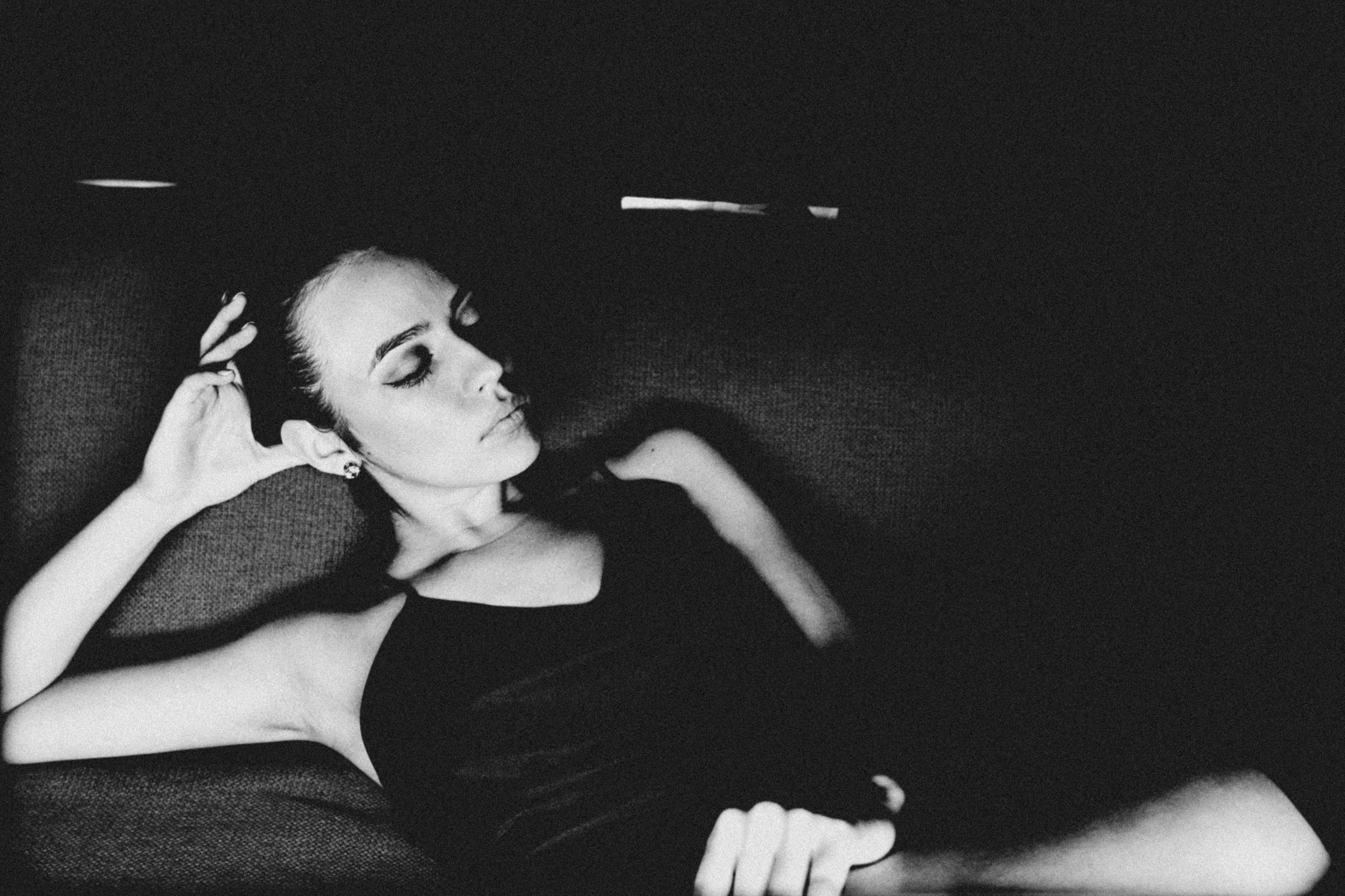 Eine Frau lehnt sich im Dunkeln zurück und hat die Augen geschlossen.