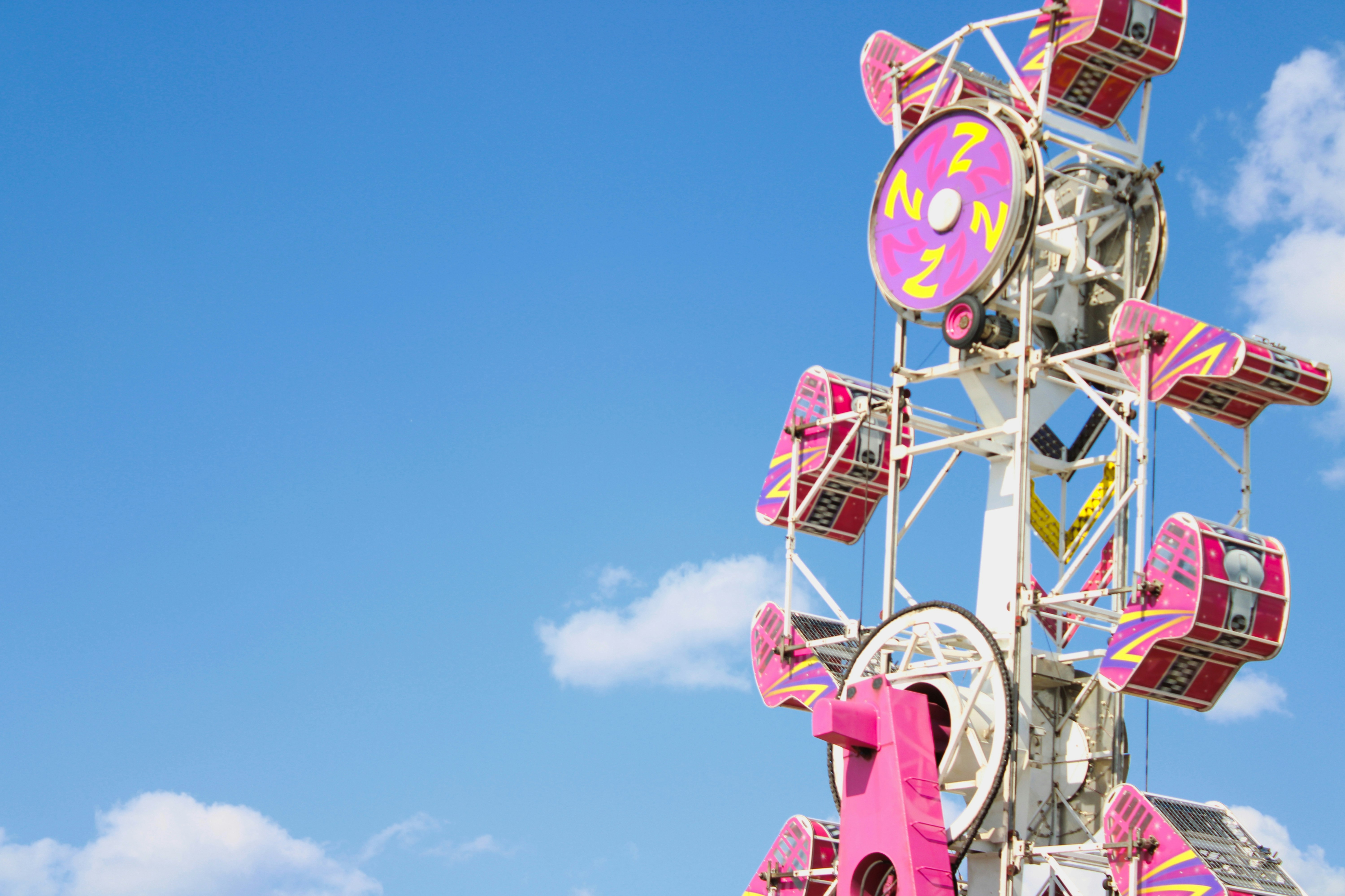 A pink carnival ride against a blue sky