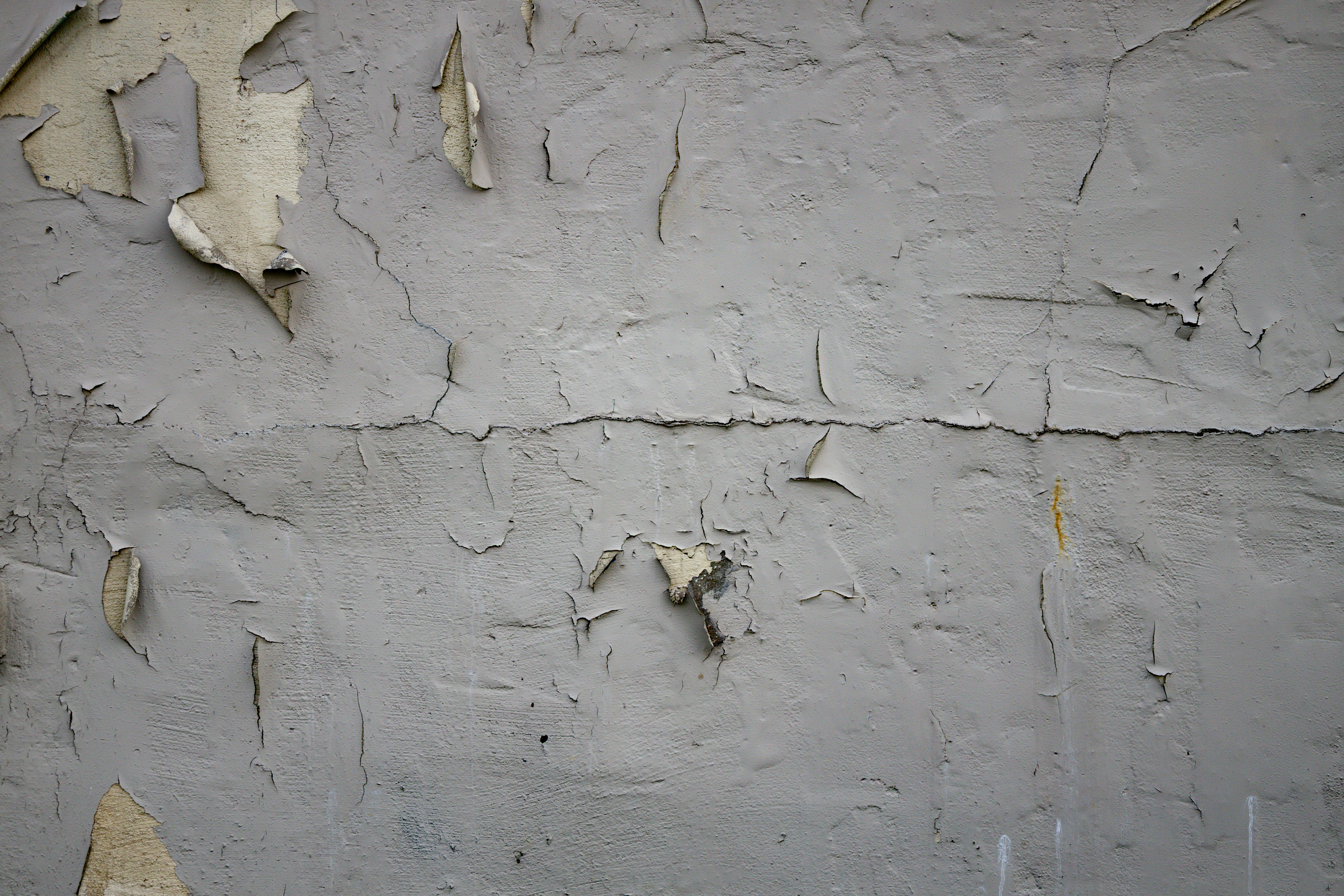 Peeling paint on a textured gray wall