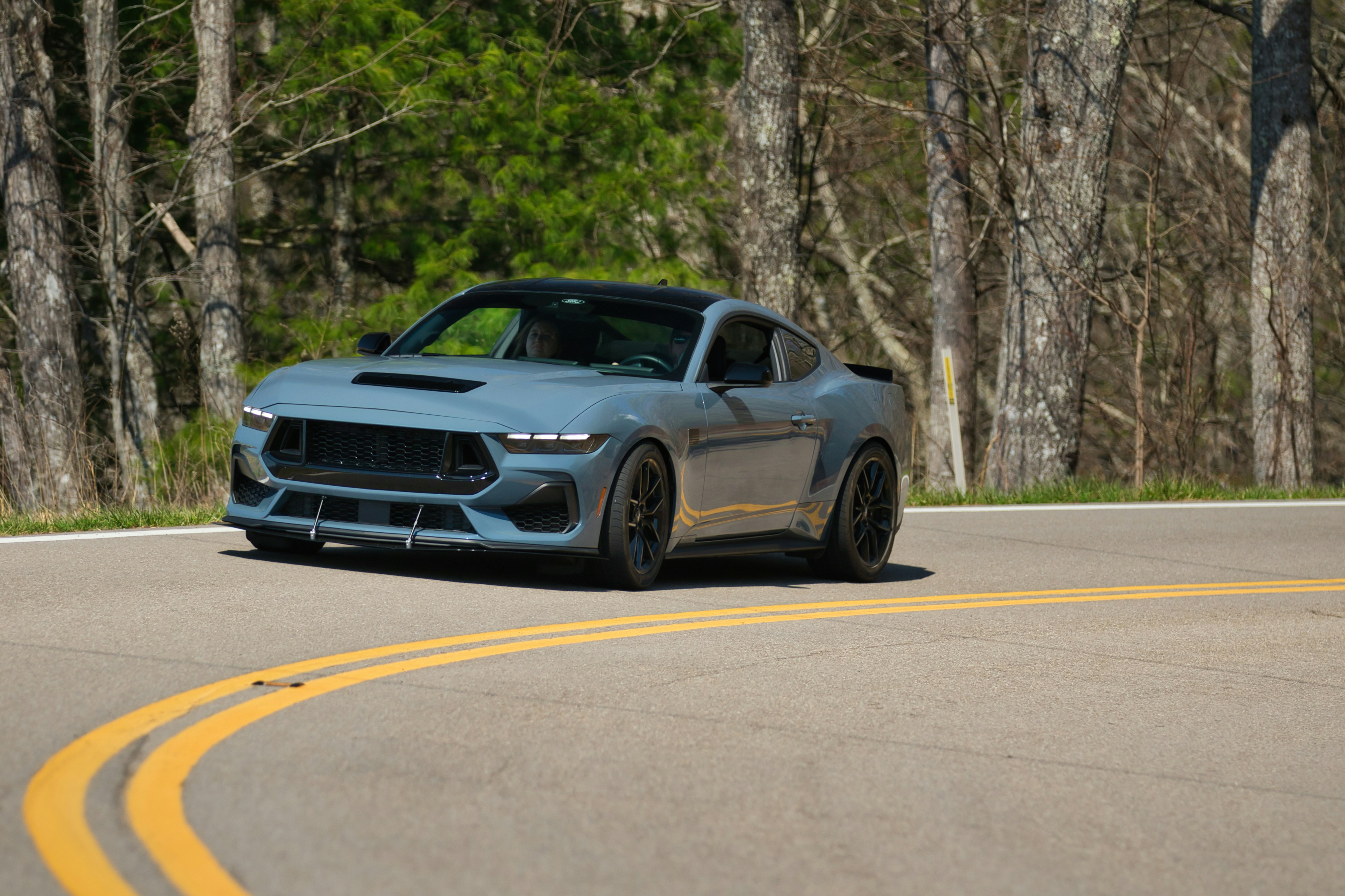 Ein blauer Sportwagen fährt auf einer kurvigen Straße.