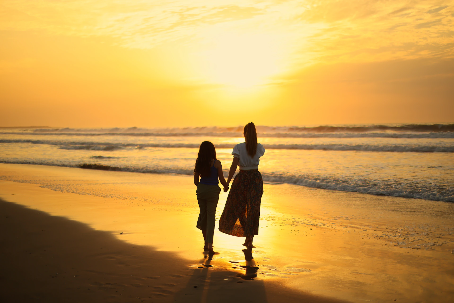 Two people walking on a beach at sunset