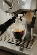Espresso brewing in a glass cup from a coffee machine.