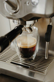 Espresso brewing in a glass cup from a coffee machine.