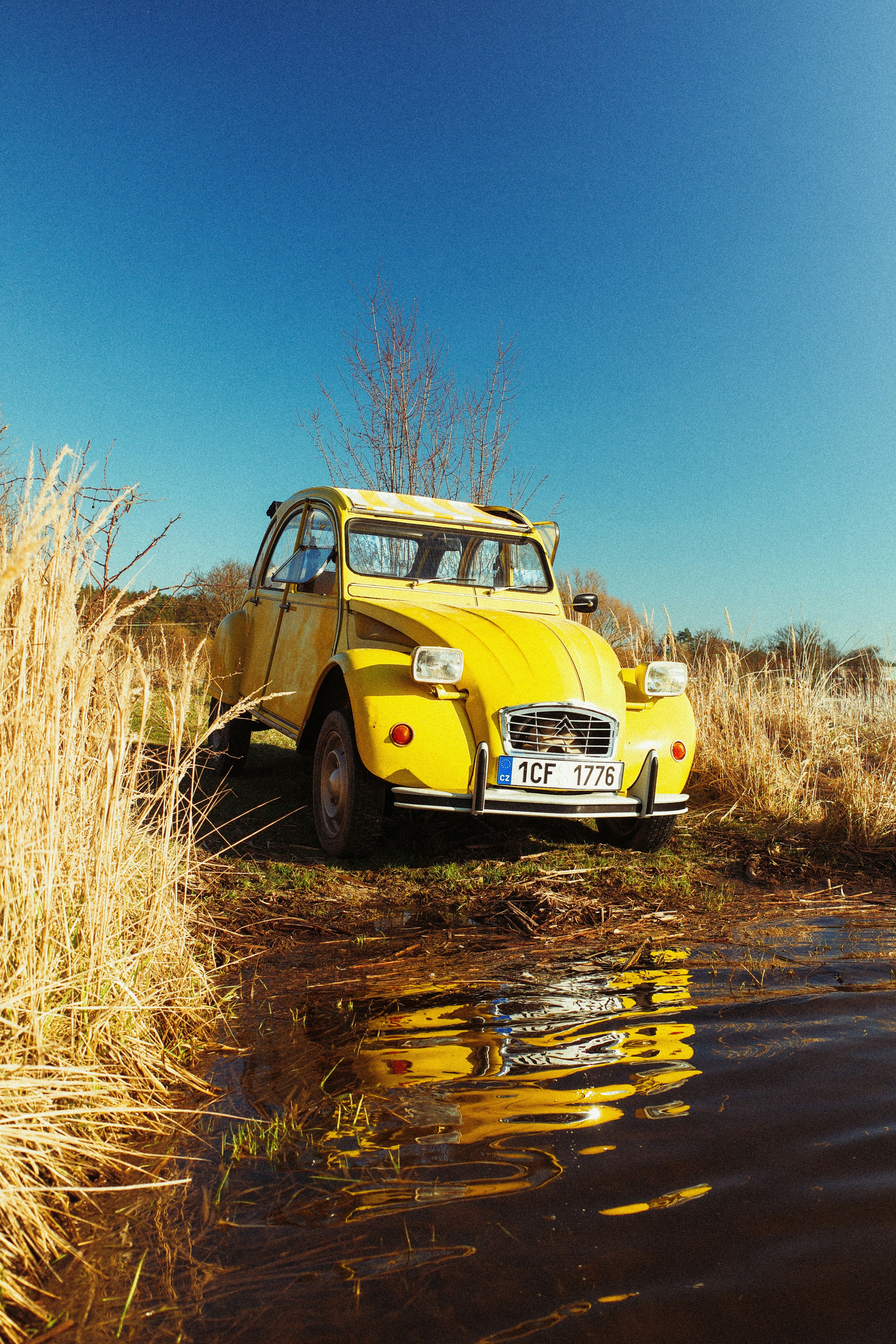 A yellow vintage car parked by a body of water.