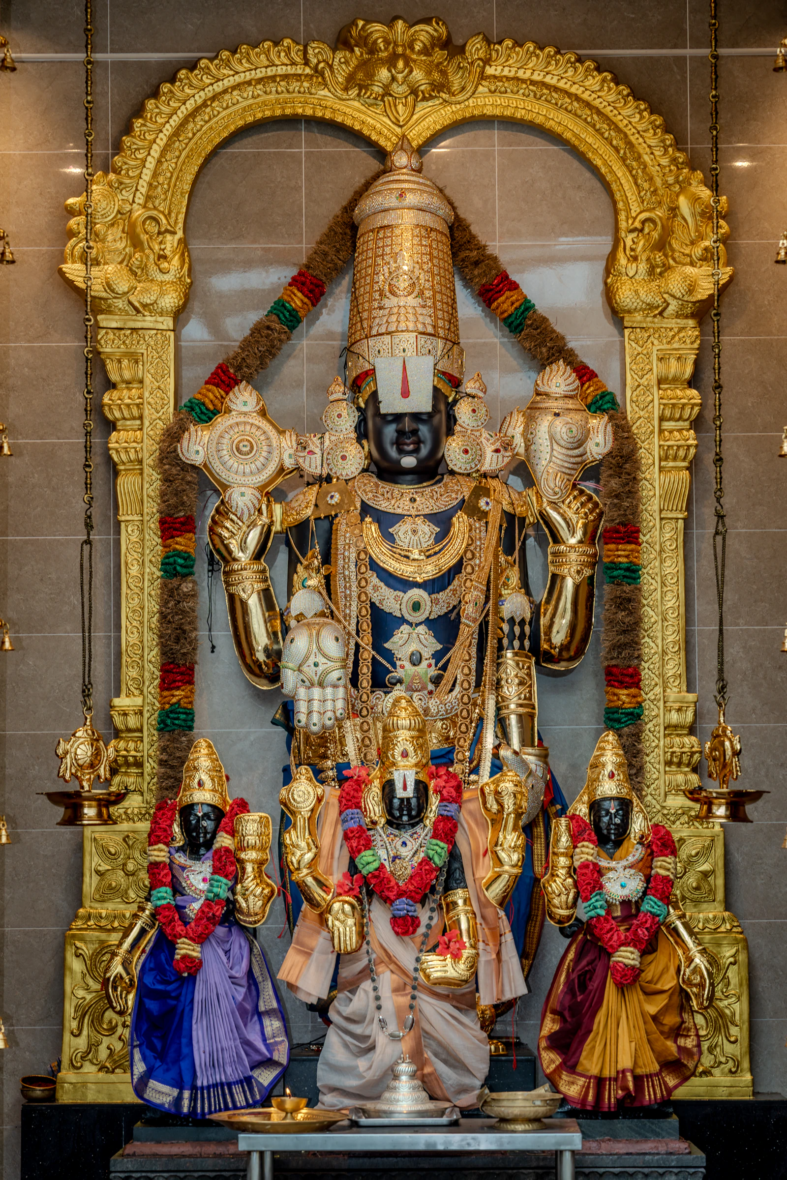 A form of Vishnu on a golden altar, with smaller idols in front.