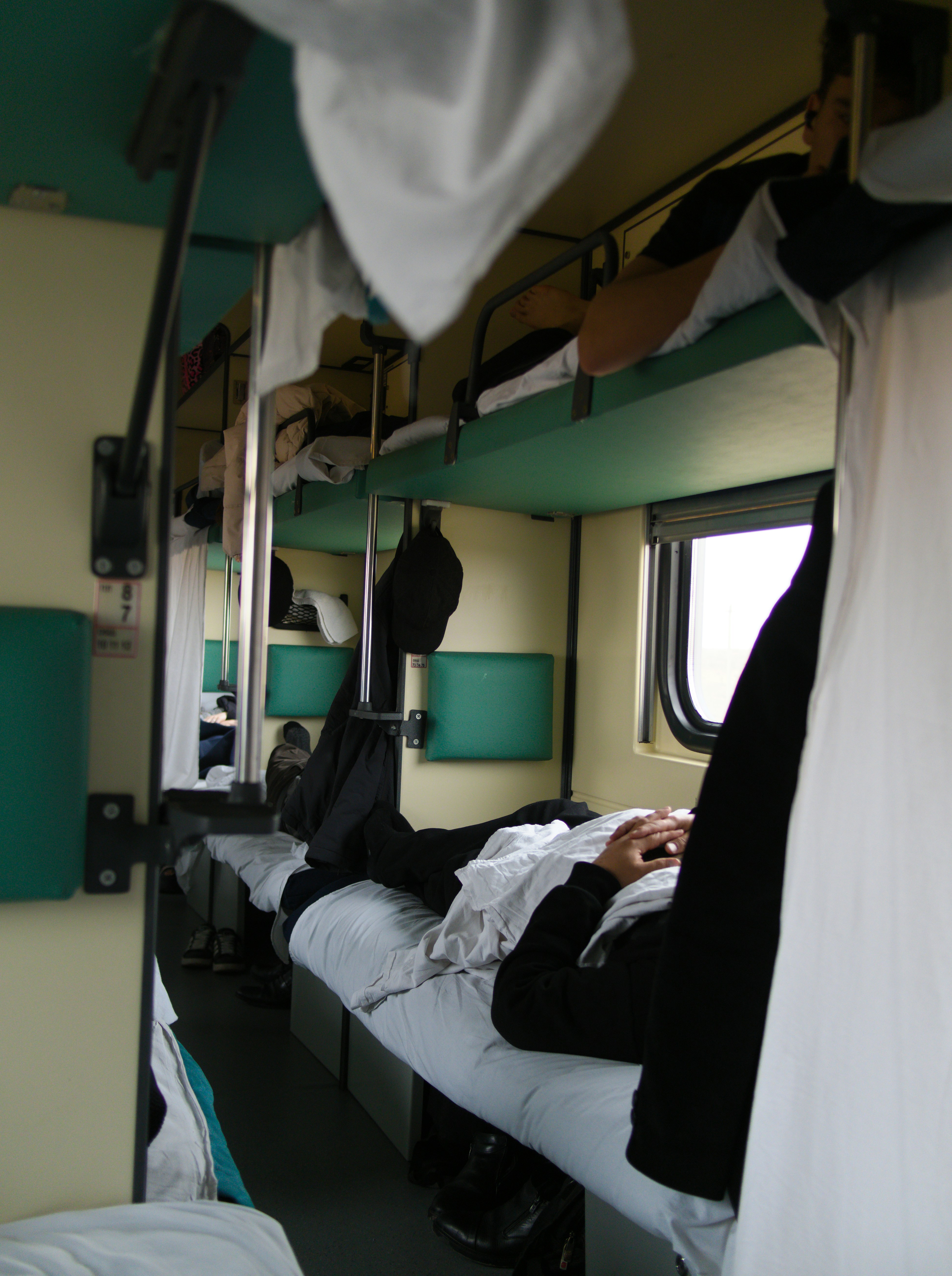 Person sleeping in a train compartment with bunk beds