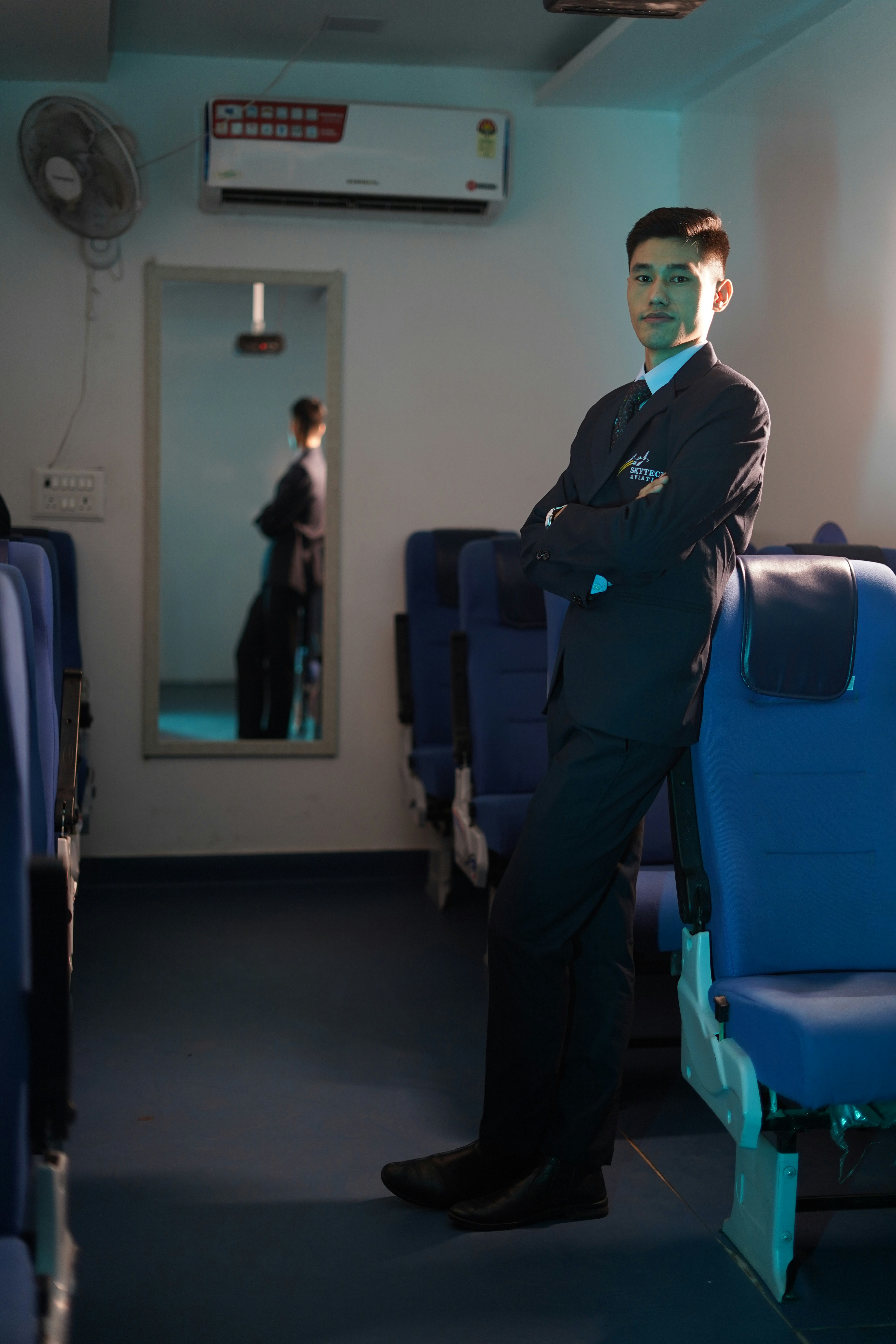 Man in suit leans against seats in an empty room.