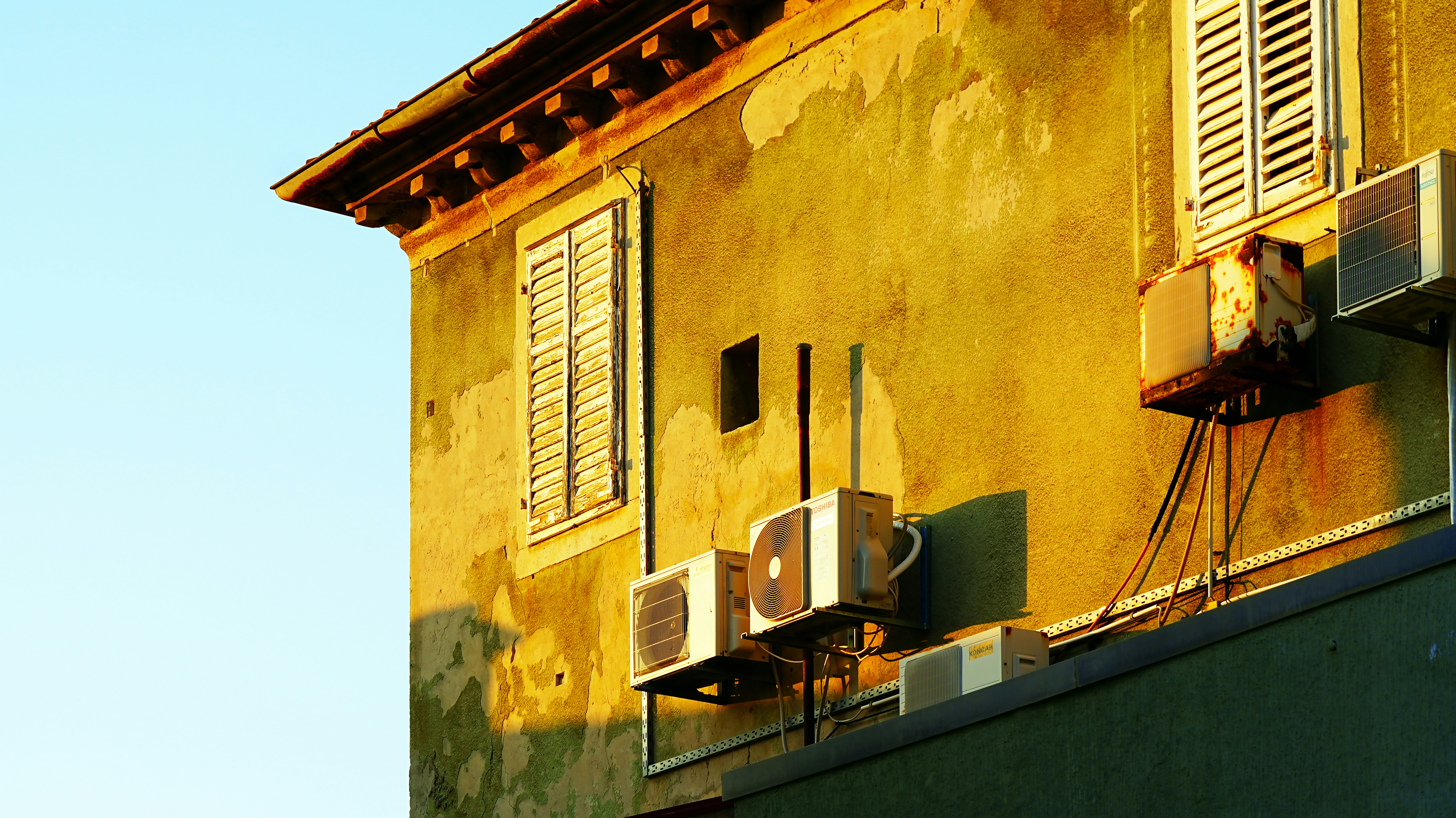 La lumière du soleil éclaire un vieux bâtiment équipé de climatiseurs.