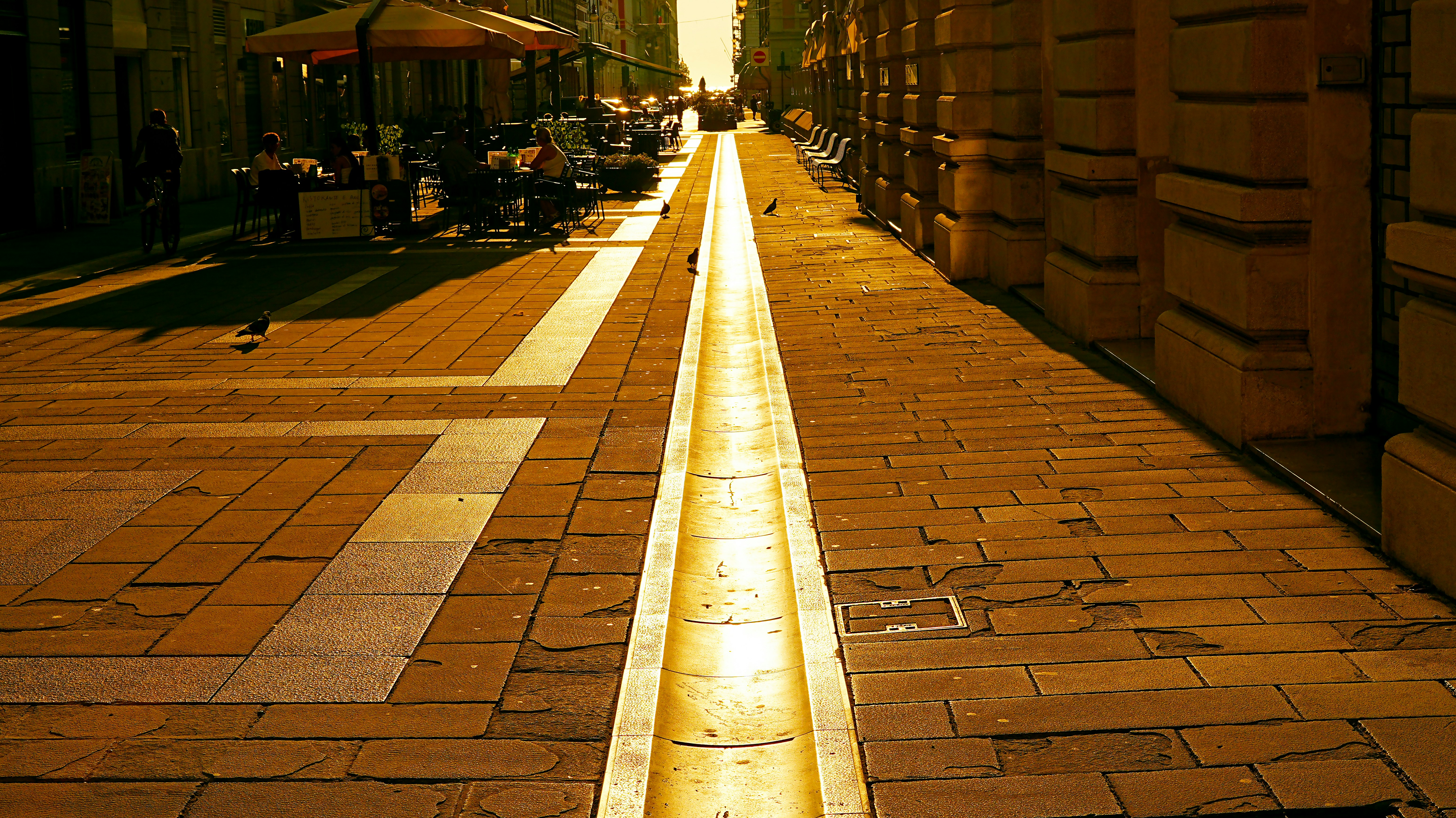 Une rue ensoleillée avec un canal de drainage doré.
