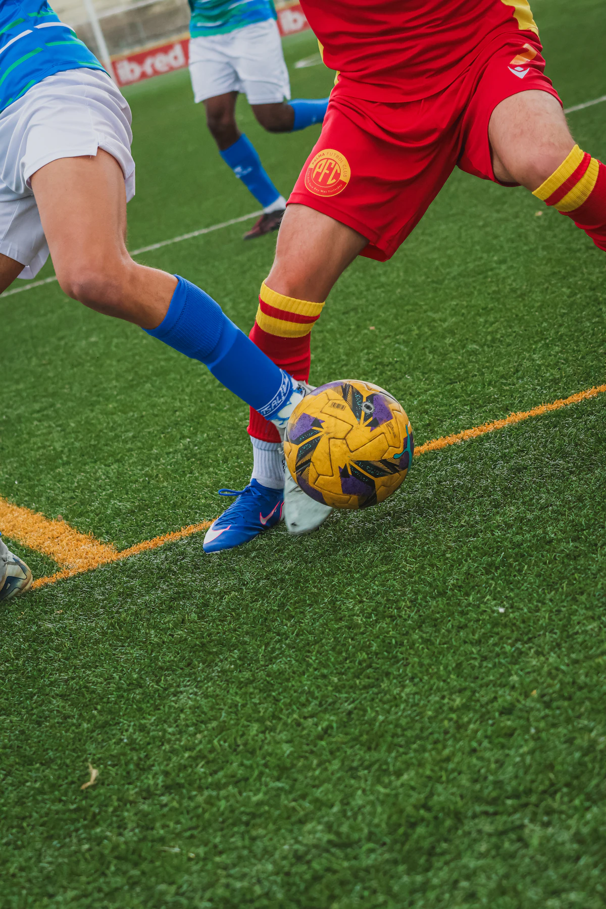 相手の足がボールへ伸びるサッカーの1対1を写したイメージ写真
