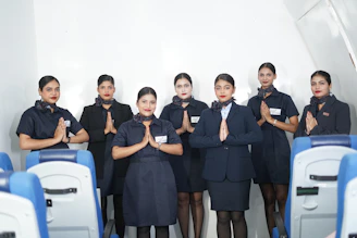 Flight attendants in uniform greeting passengers on airplane