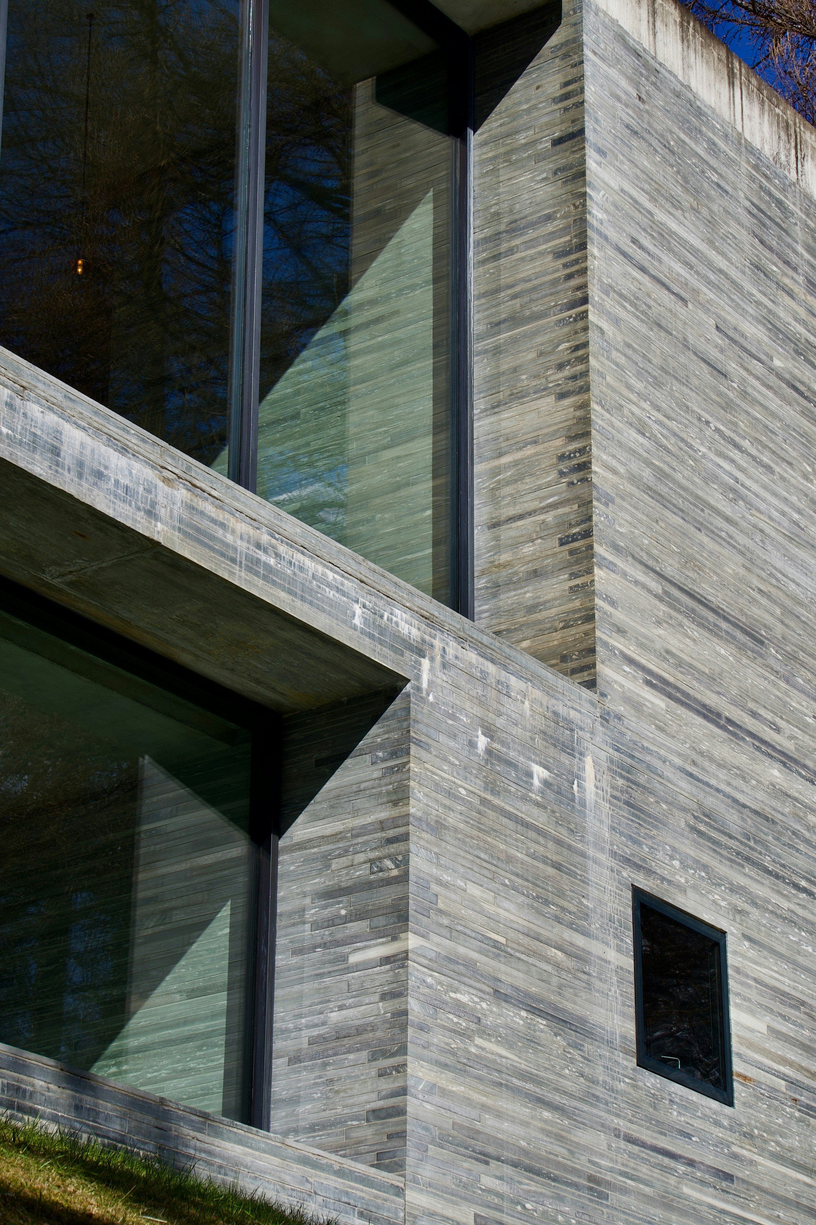 A modern building facade with layered grey stone tiles and large glass windows