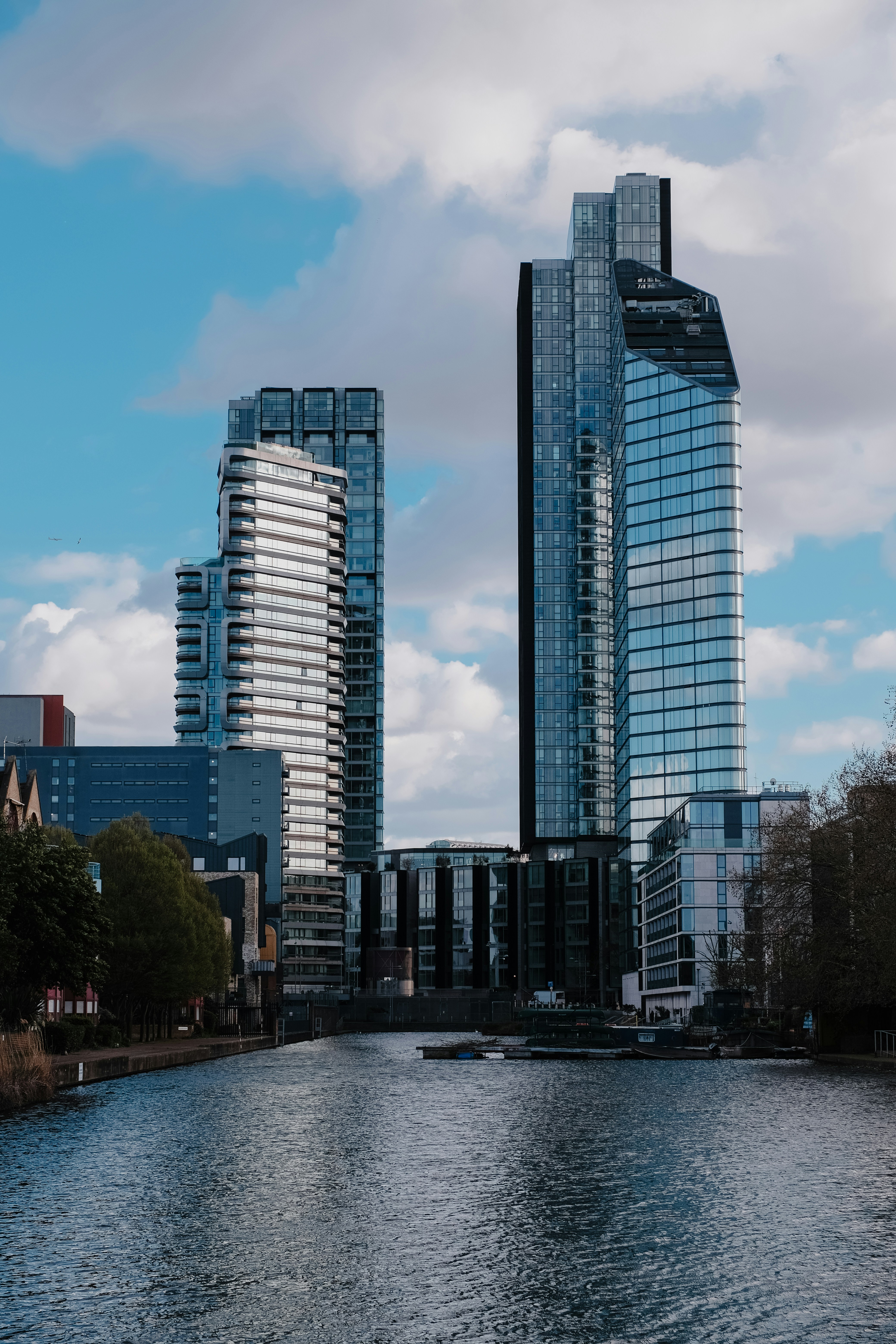 흐린 하늘 아래 잔잔한 강을 따라 현대식 고층 빌딩들이 늘어서 있습니다.