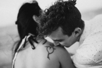 Man kissing woman's shoulder with tattoo