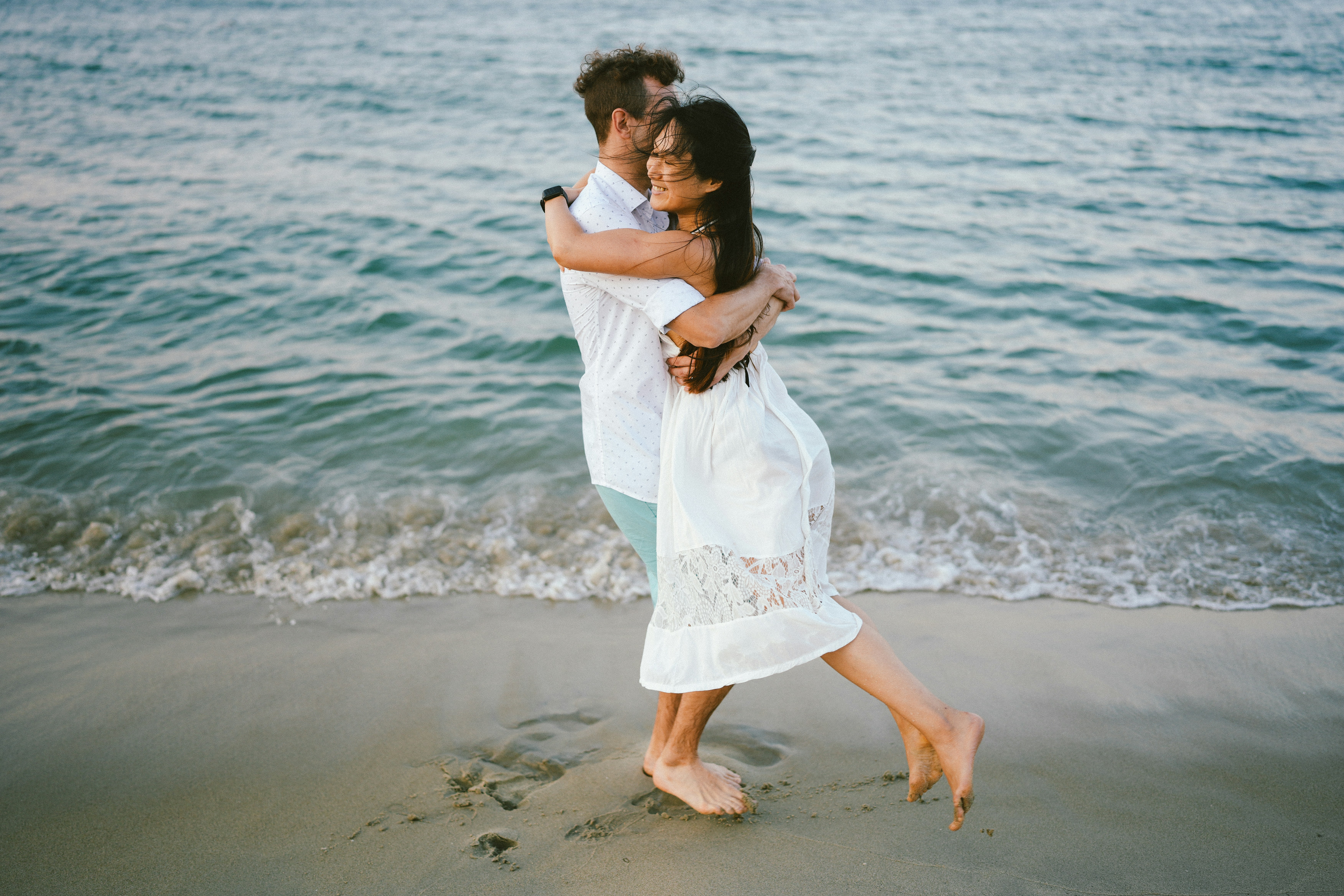 A couple embraces on a sandy beach by the ocean. photo  Free Summer Image  on Unsplash