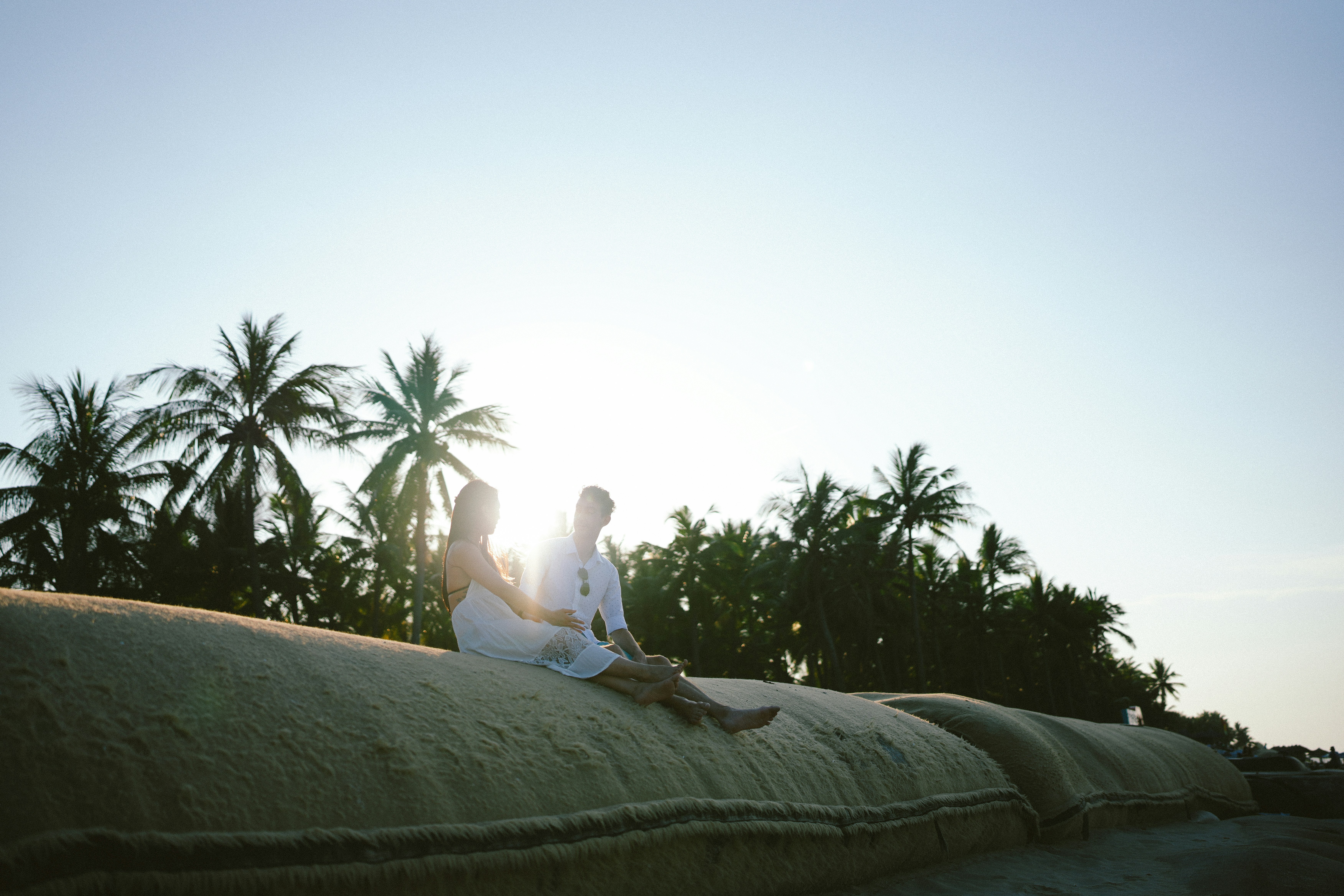 ヤシの木のある砂丘に座るカップル。