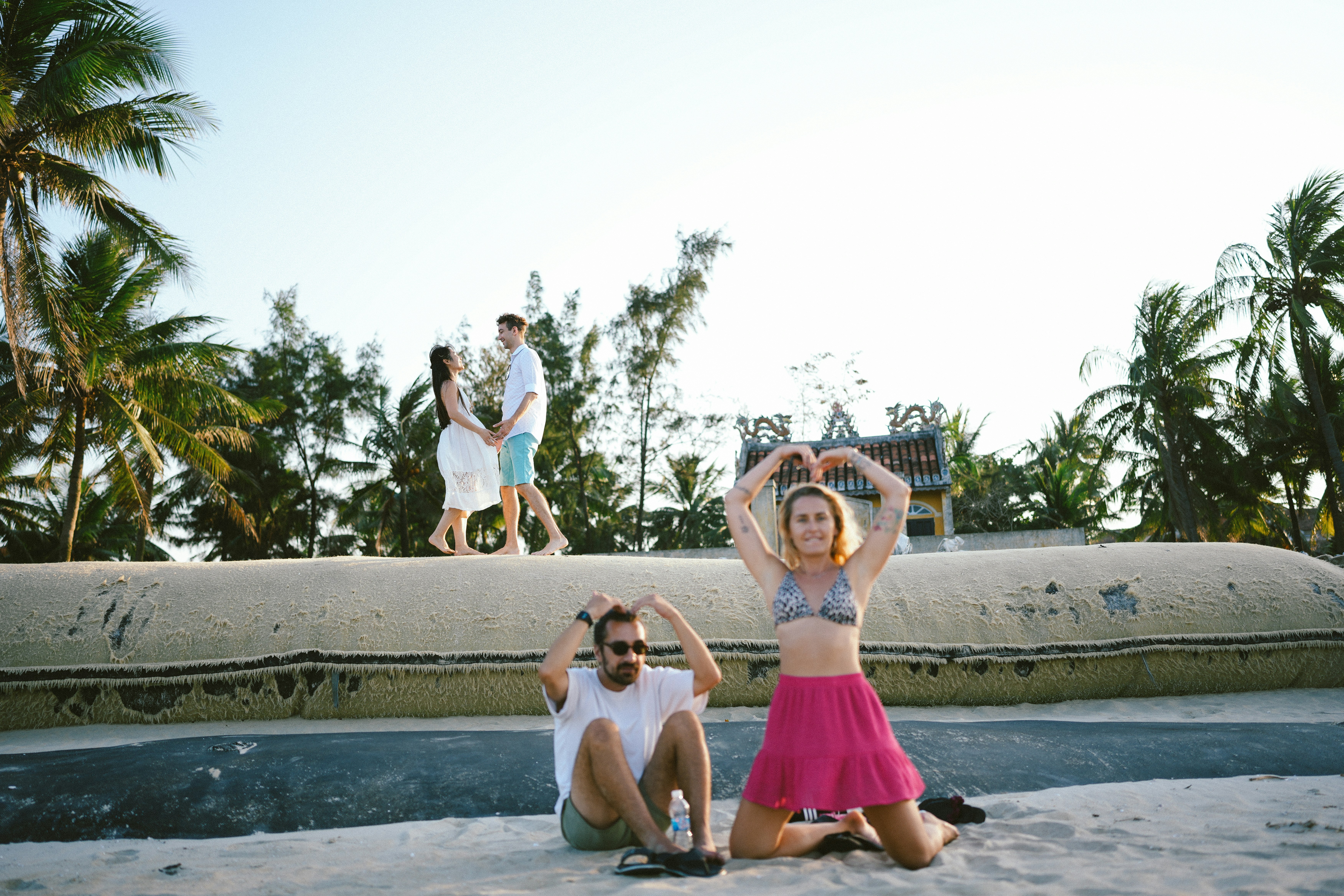 ビーチで手を合わせてハート型を作るカップル