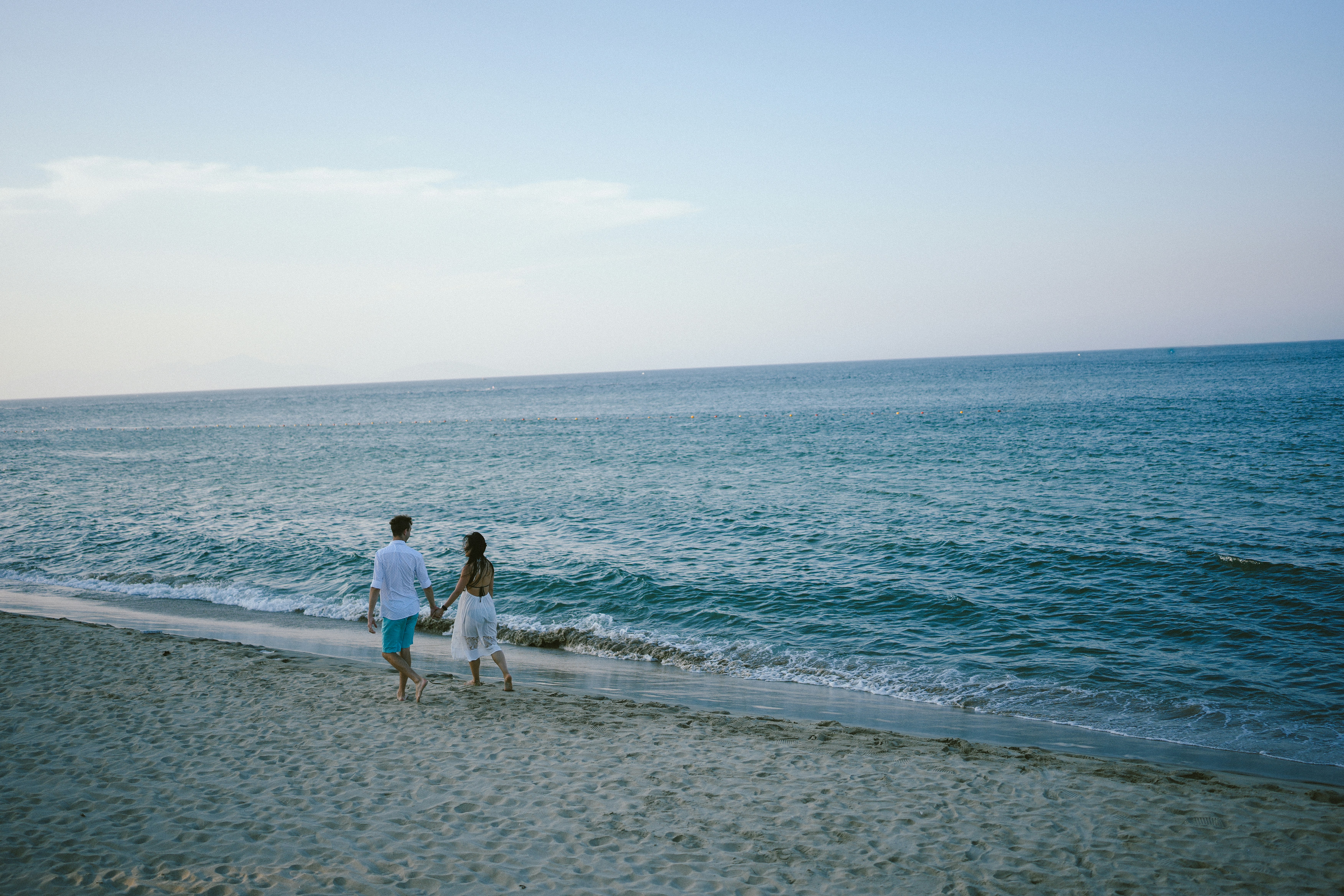 海辺の砂浜を歩くカップル