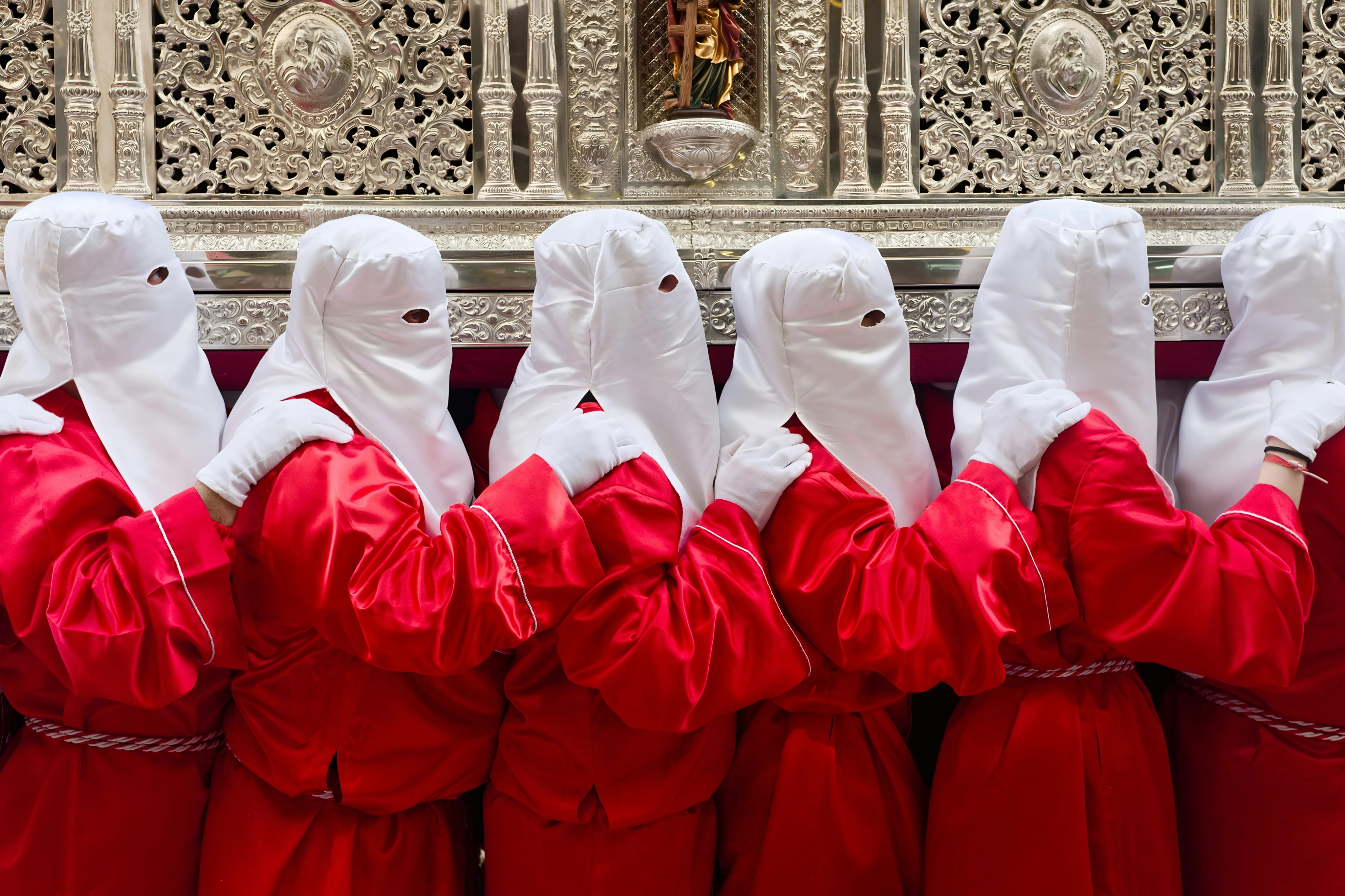 People in red robes and white hoods during a procession.