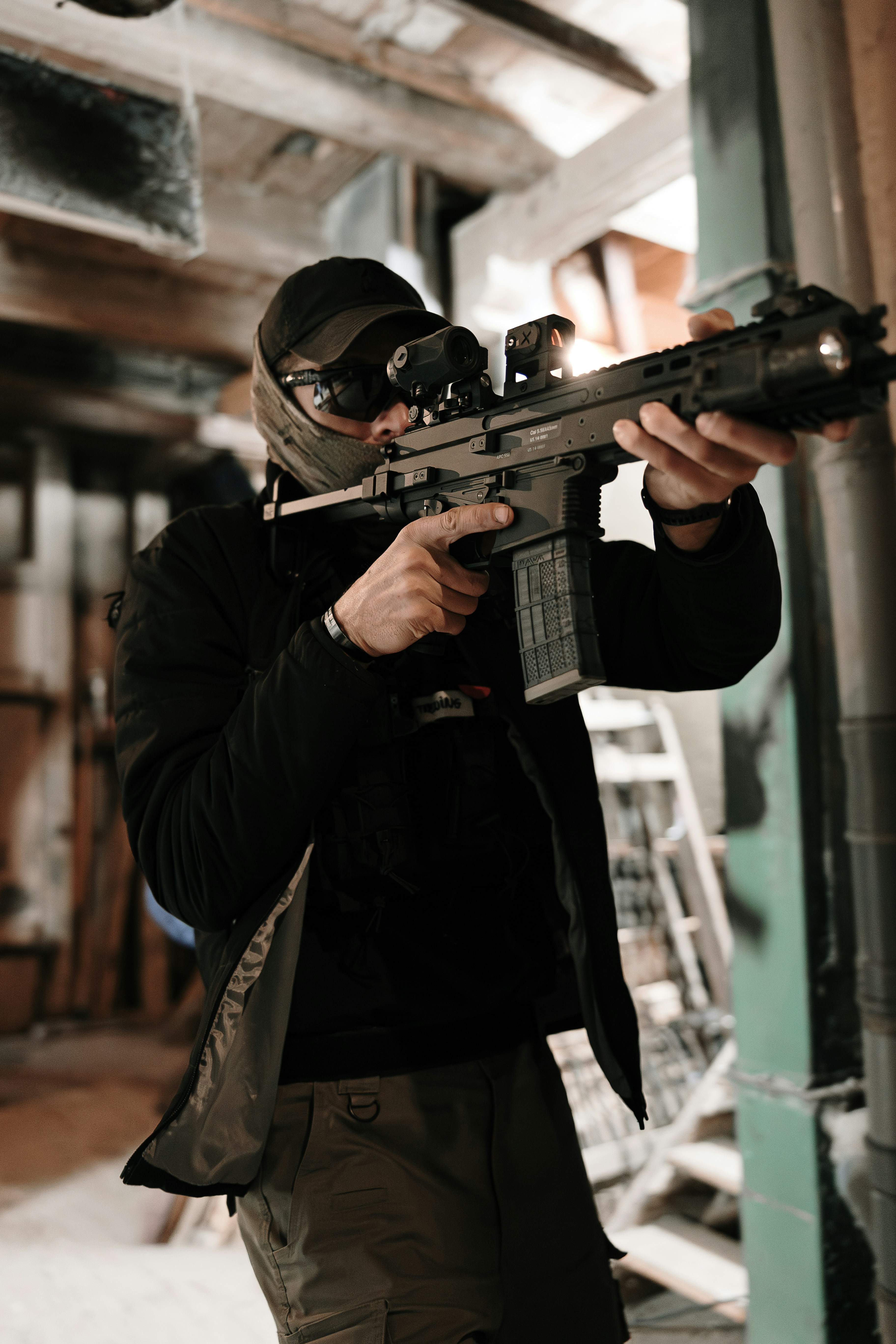 屋内でスコープ付きの戦術ライフルを狙う男。