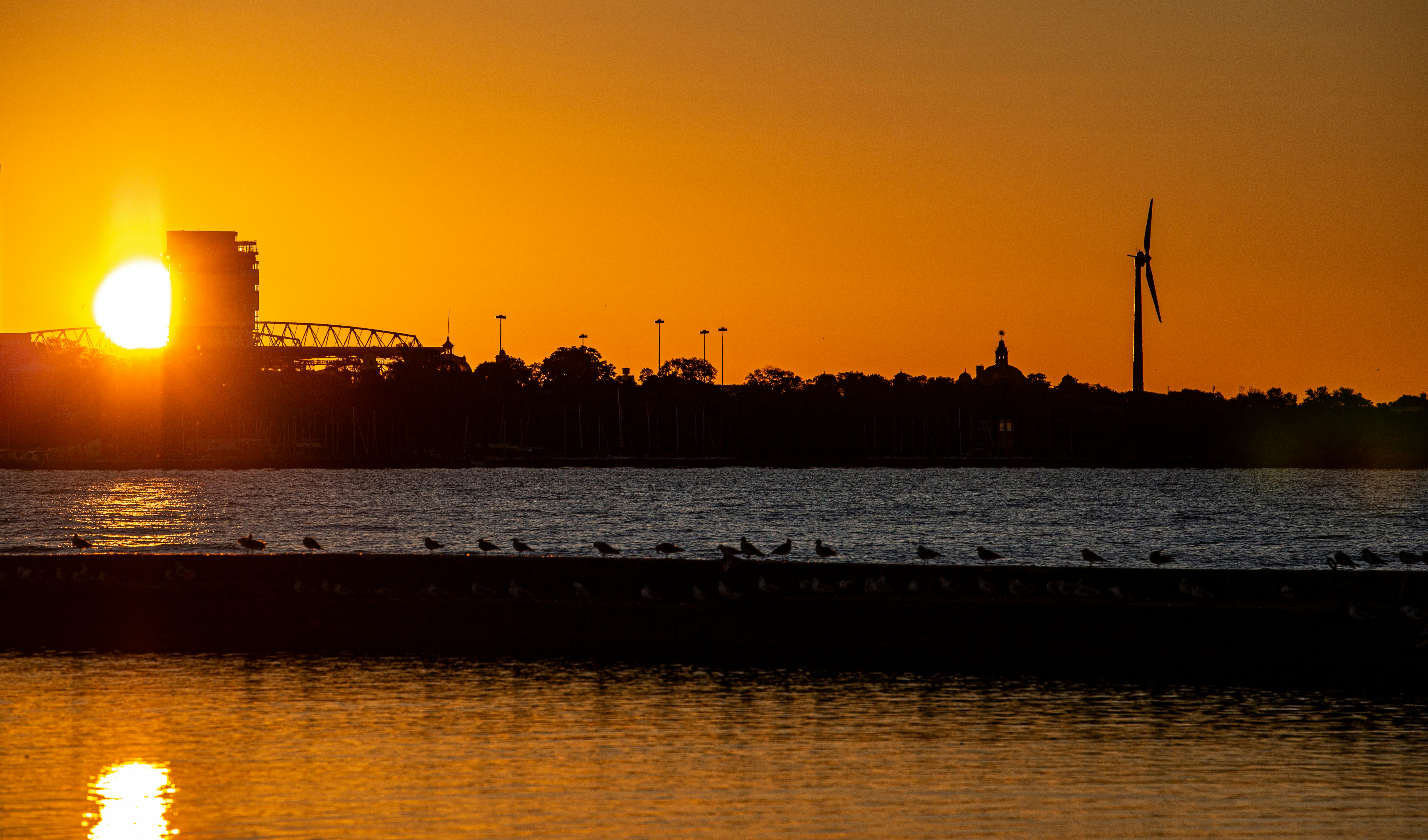 Sunset over a calm body of water with city skyline.