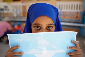 Young girl in blue hijab holds somali flag