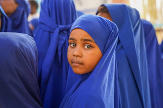 Young girl in a blue hijab looks at the camera