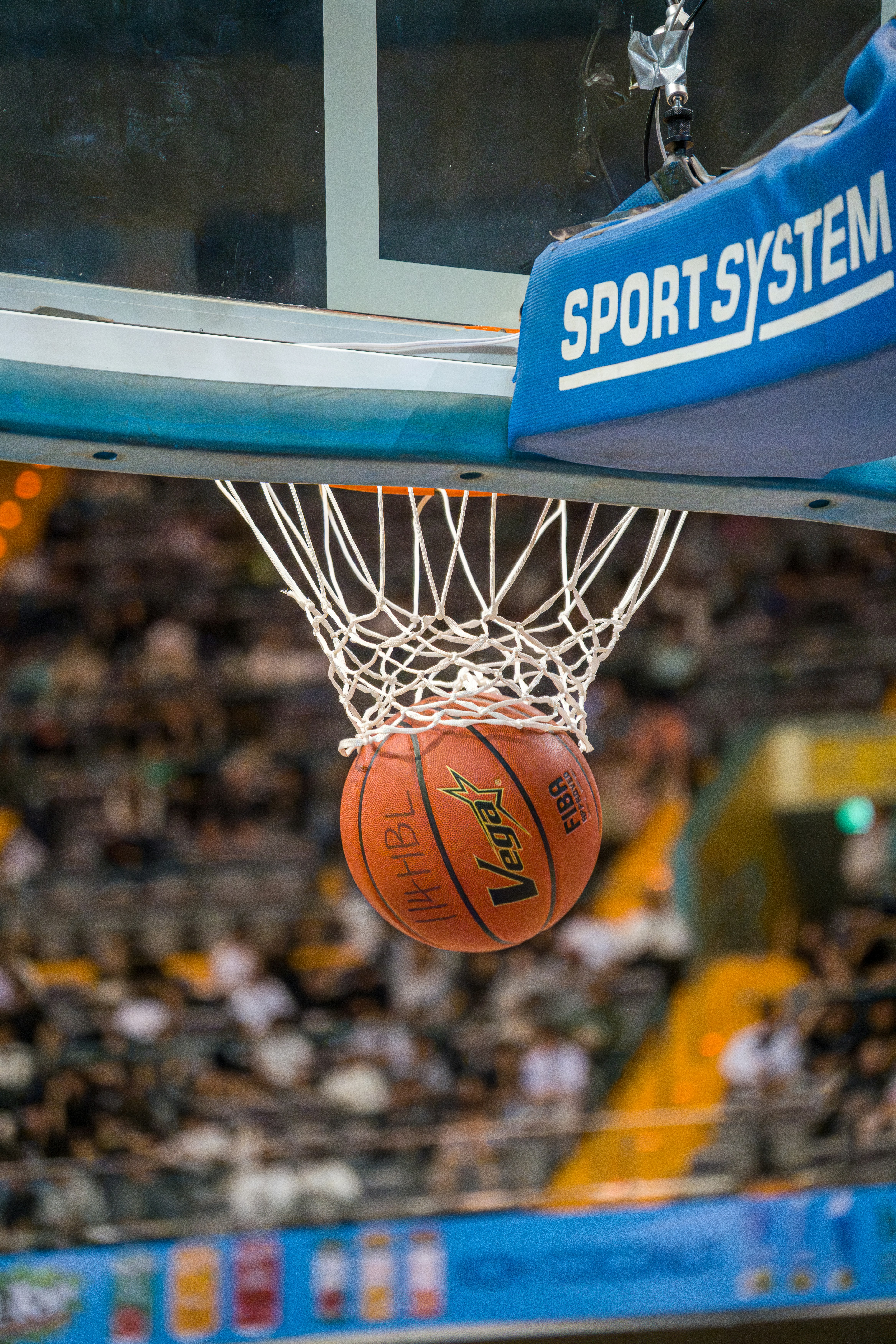 Basketball going through the net during a game.