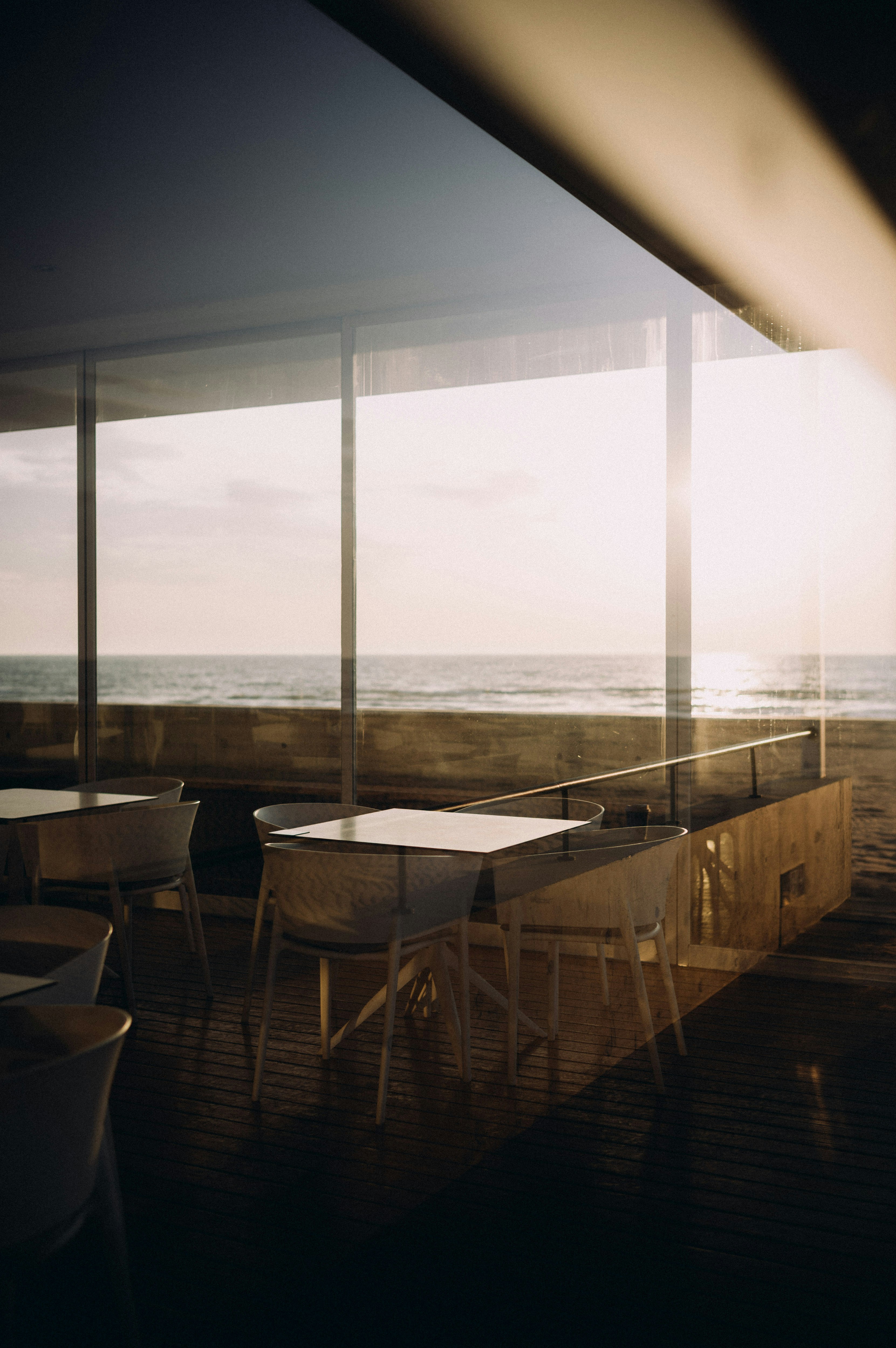 Empty tables and chairs inside a beachfront cafe.