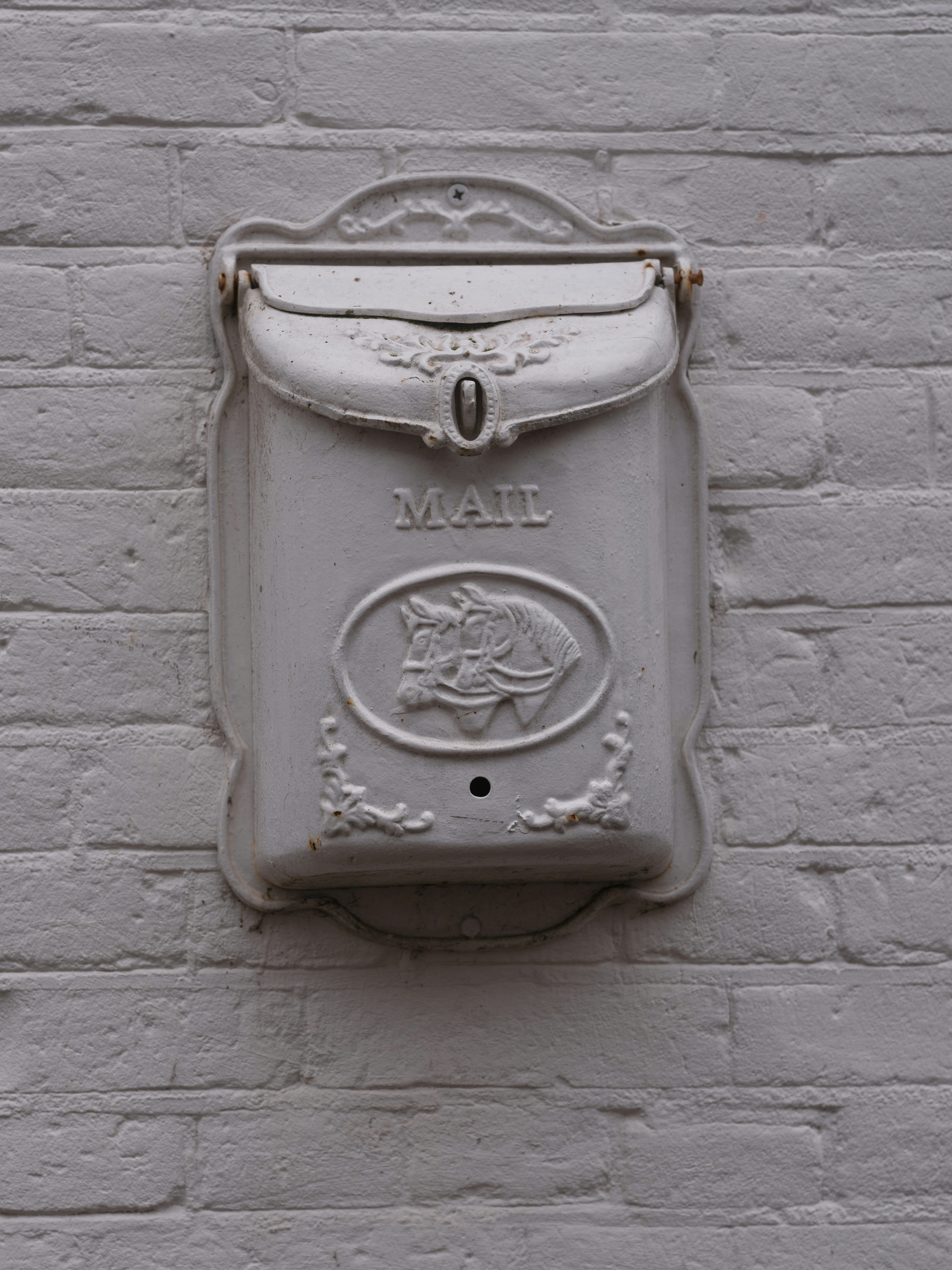 Buzón blanco ornamentado montado en una pared de ladrillo