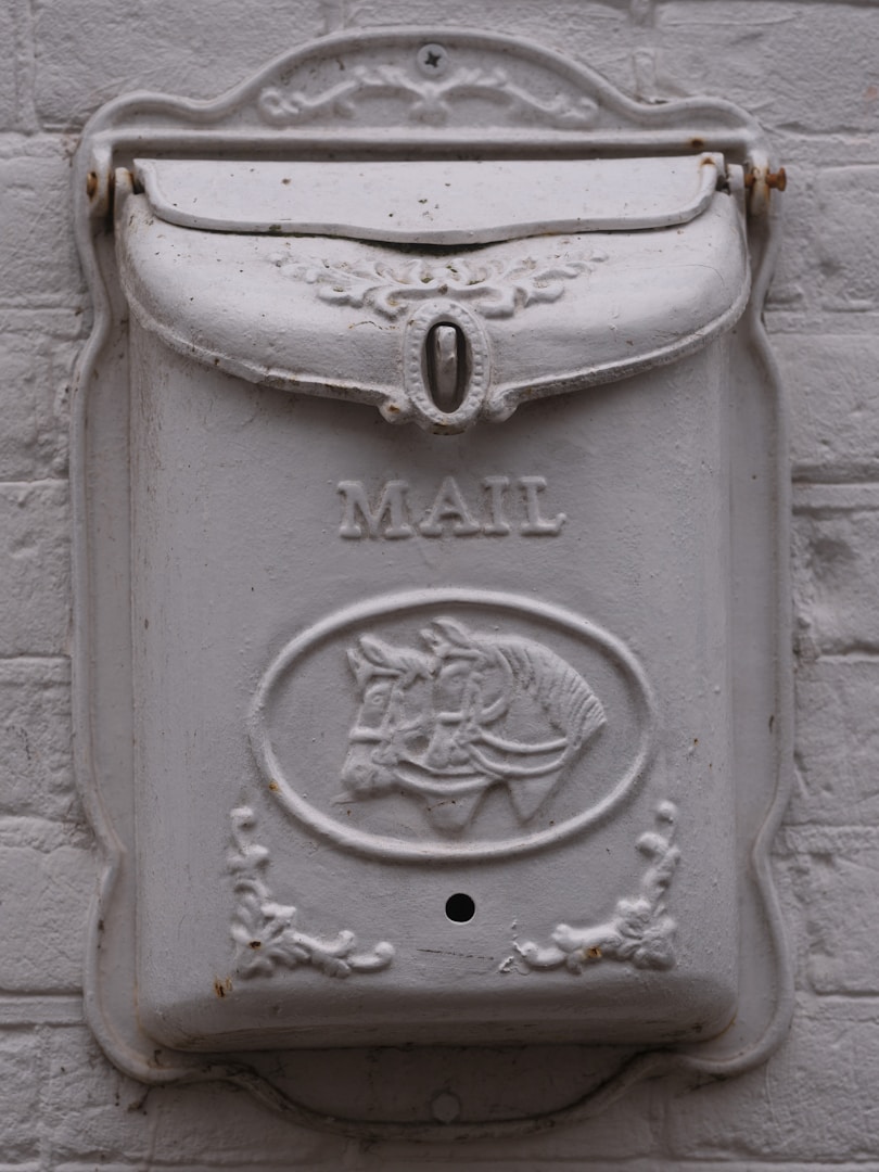 White ornate mailbox with horse emblem on brick wall