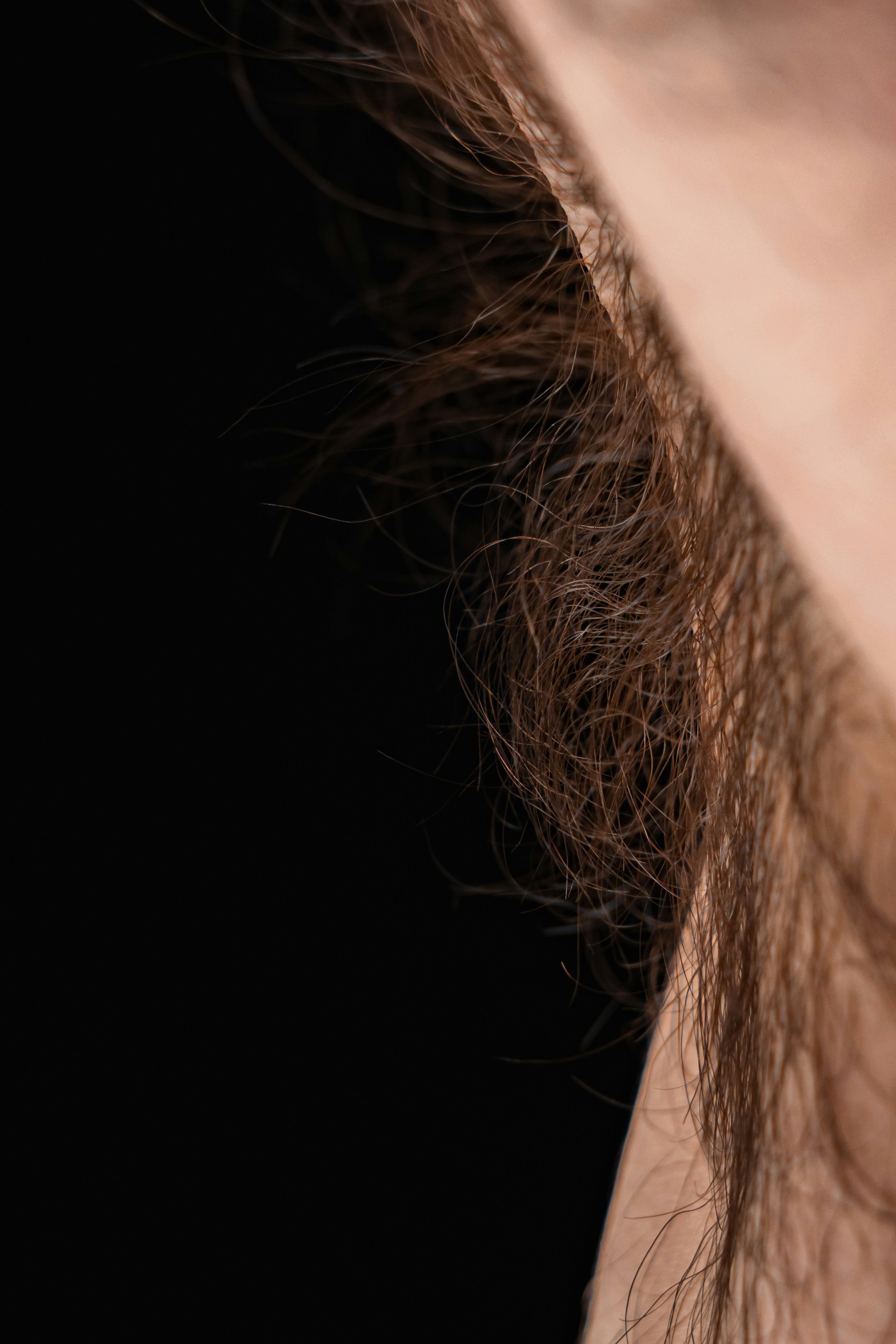Nahaufnahme von zerzaustem braunem Haar vor schwarzem Hintergrund