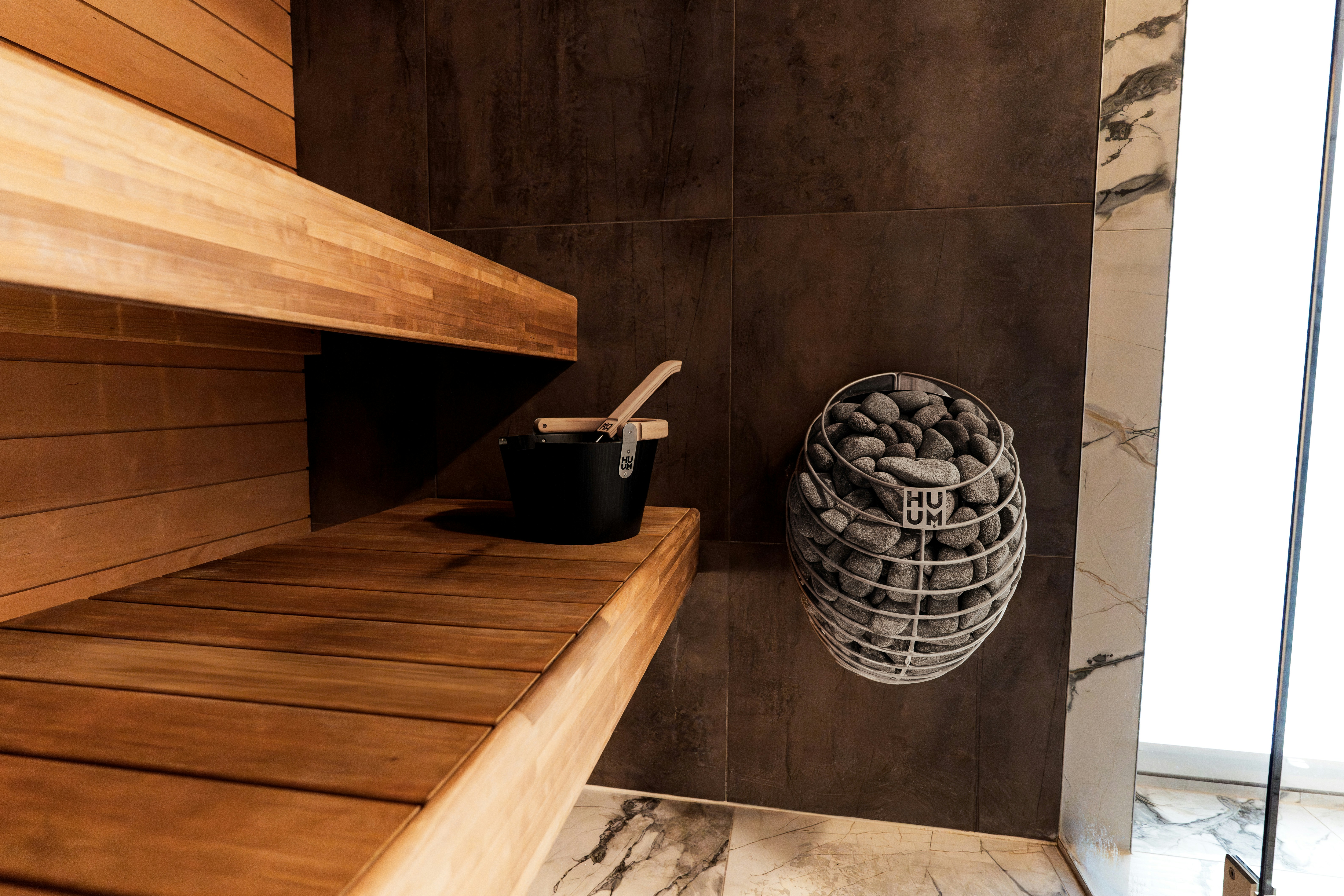 Interior sauna kayu dengan batu dan ember
