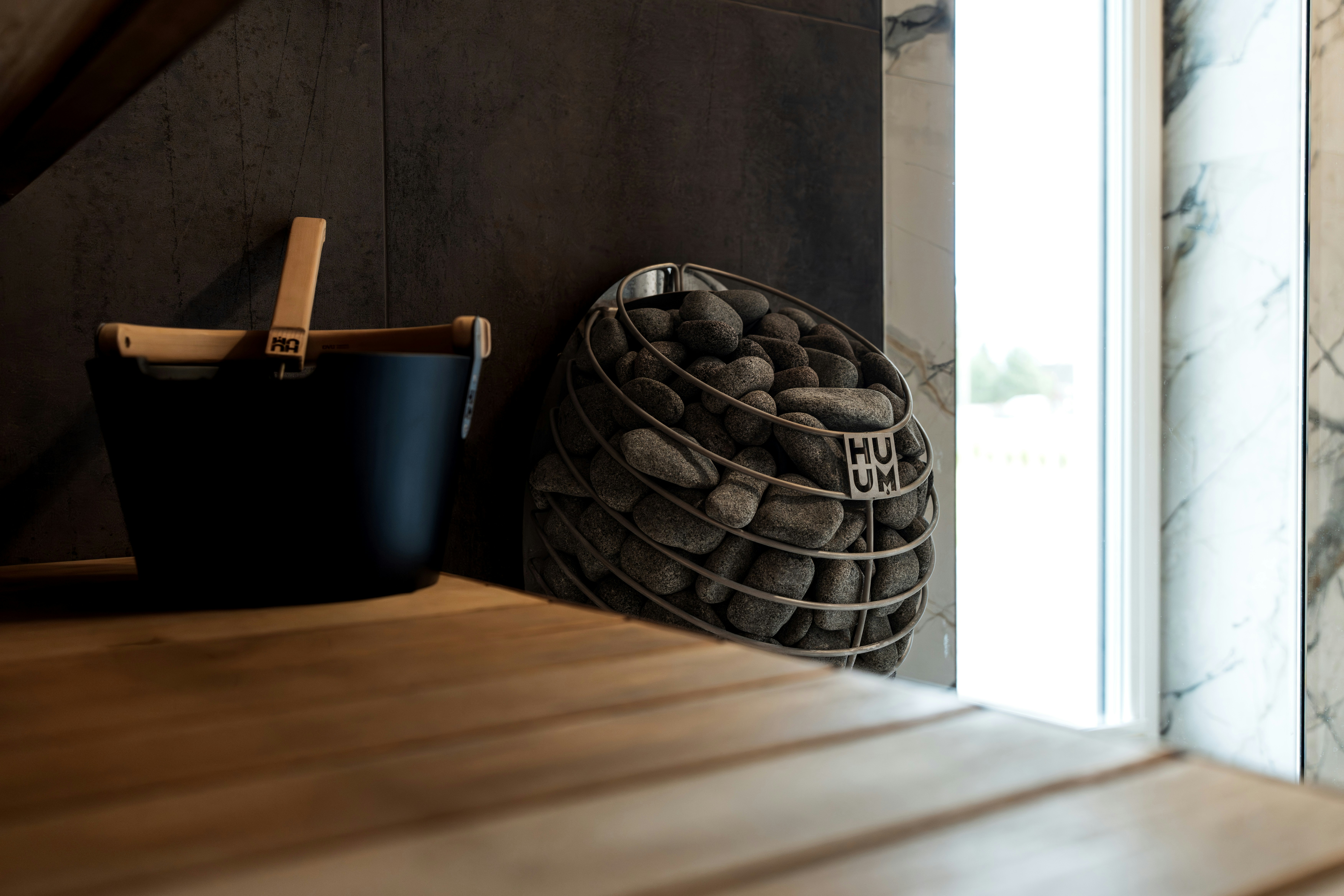 Ember sauna dan batu di sebelah bangku kayu.