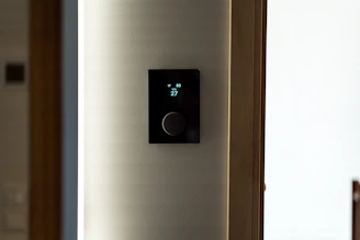 A modern black thermostat mounted on a wall