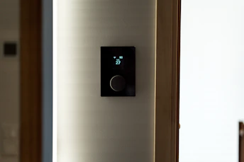A modern black thermostat mounted on a wall