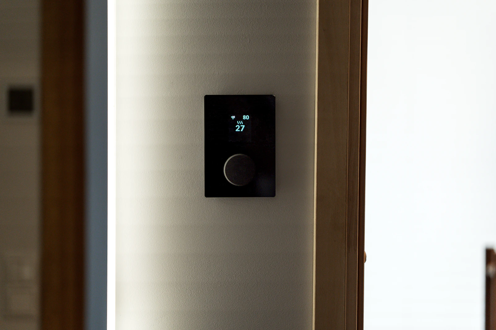 A modern smart thermostat mounted on a wall in a connected home