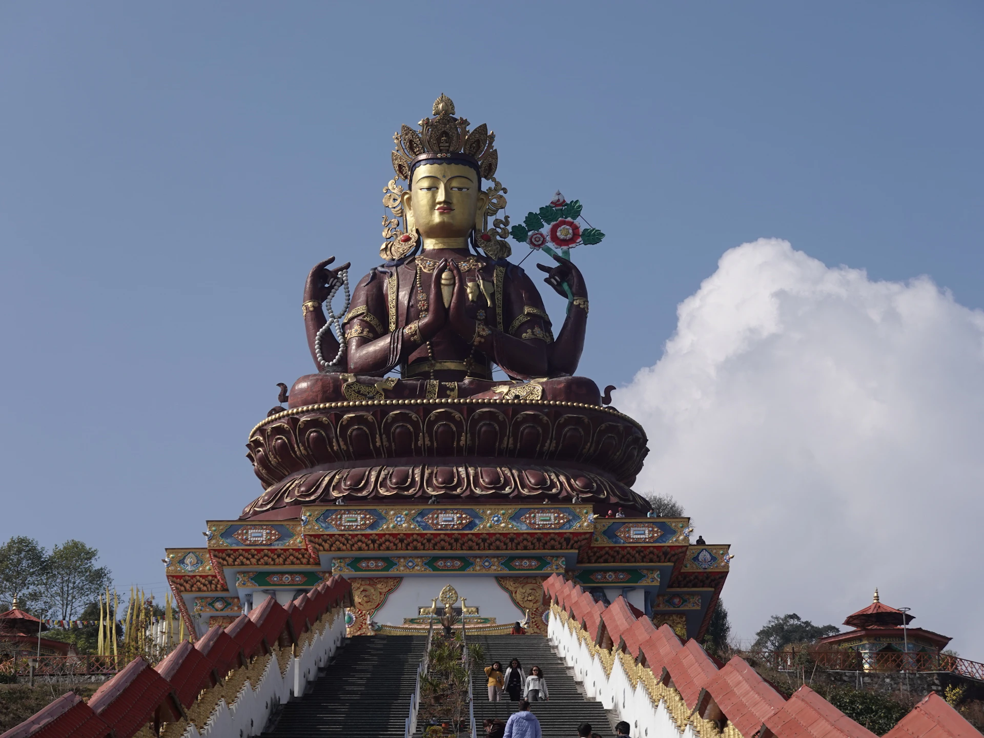 A large golden buddha statue atop a colorful pedestal.