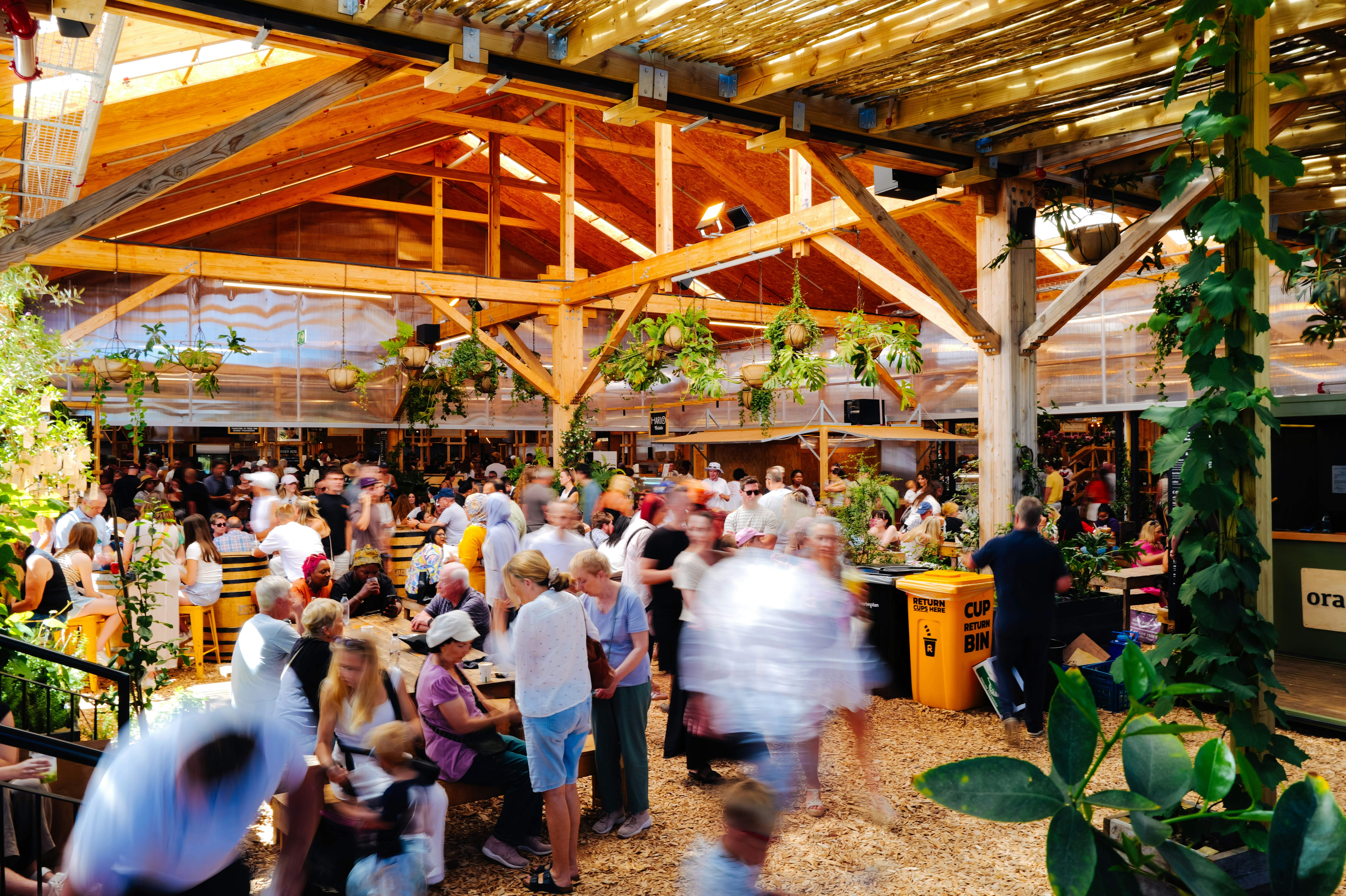 Crowded outdoor market with wooden beams and plants