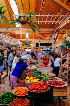 People shopping at a vibrant farmers market with fresh produce.