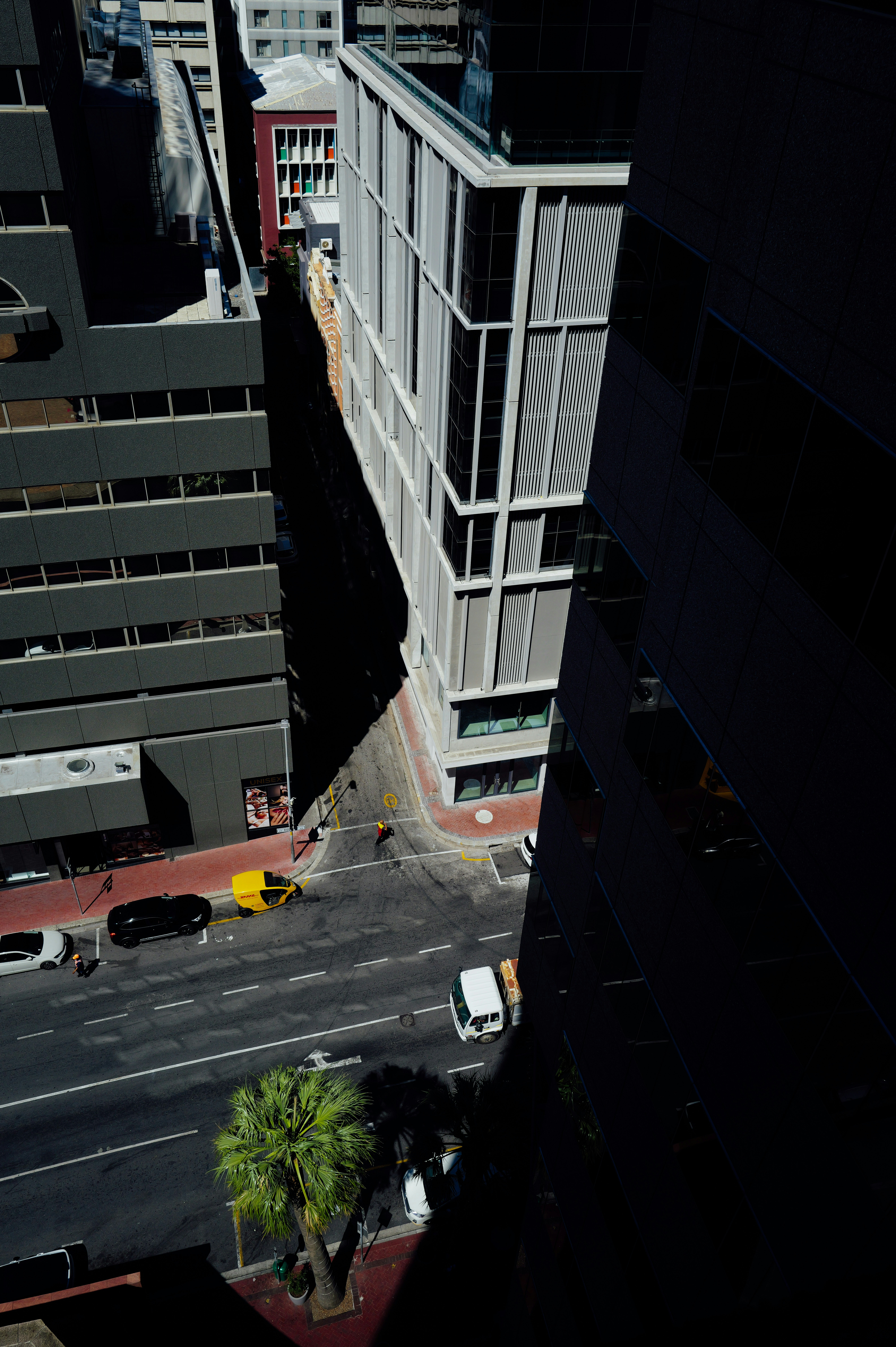 Aerial view of a city street with buildings and vehicles.