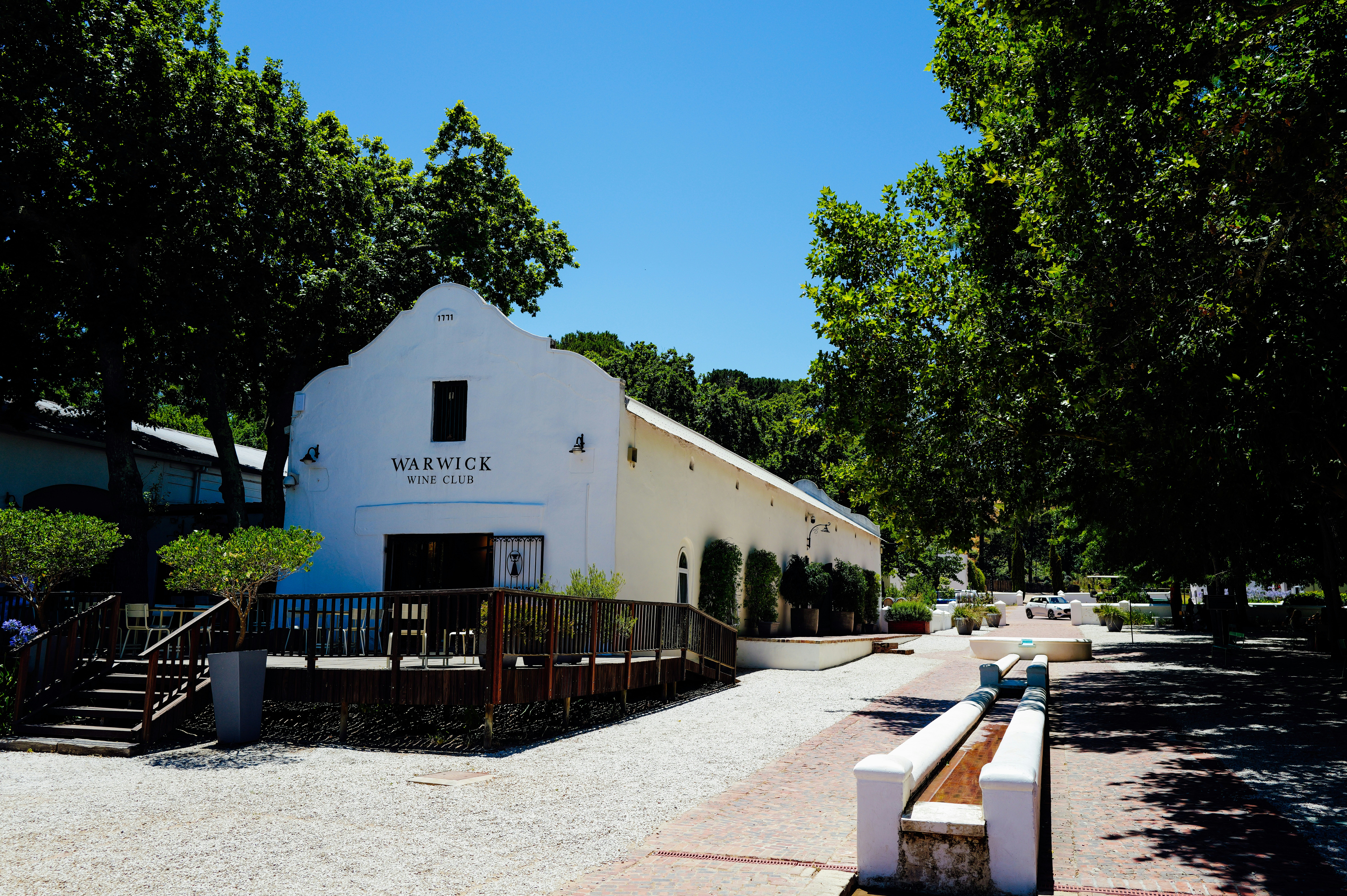 White building with outdoor seating surrounded by trees