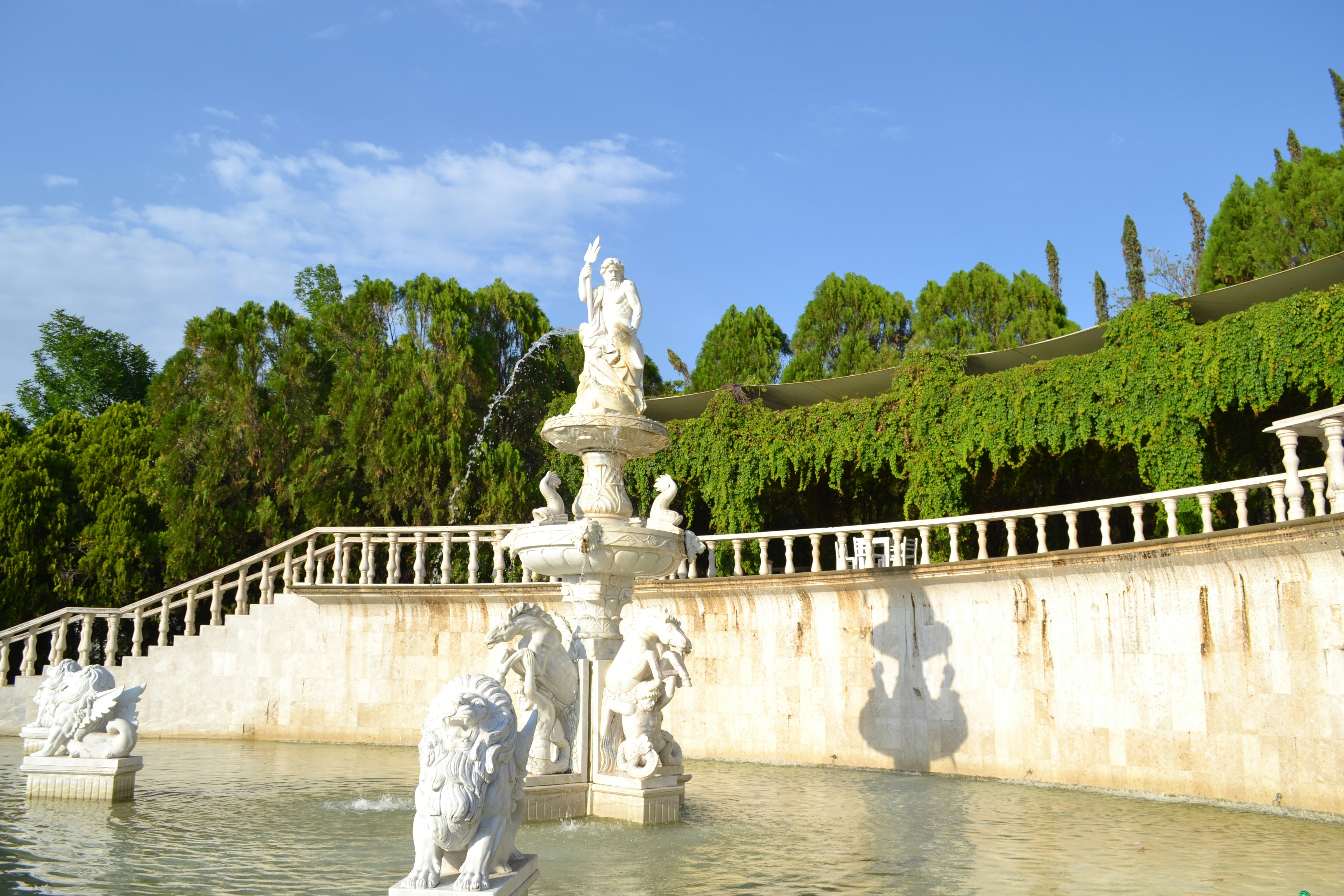 Una fontana decorativa con statue in un giardino illuminato dal sole