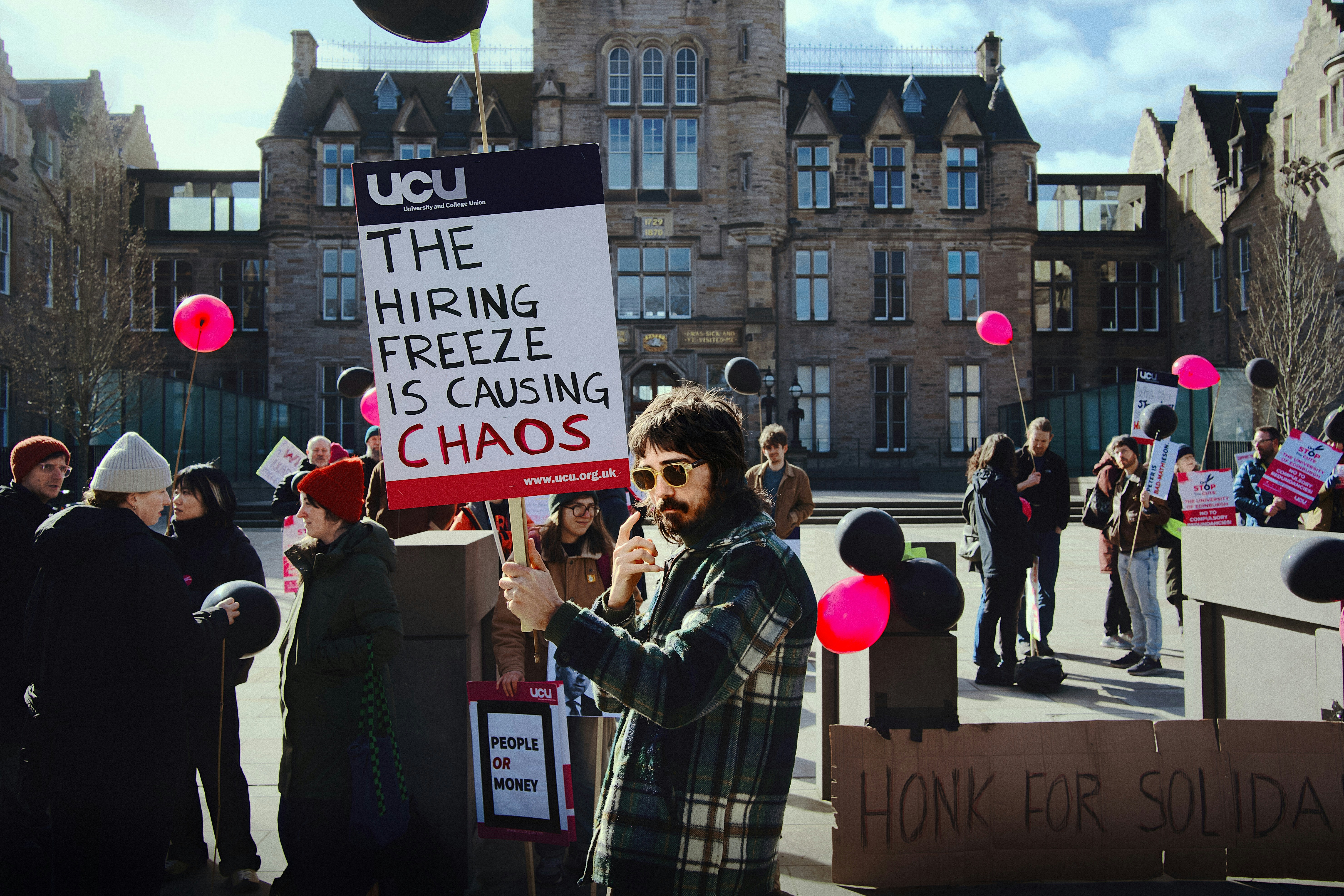 Protesters hold signs outside a building during a demonstration.